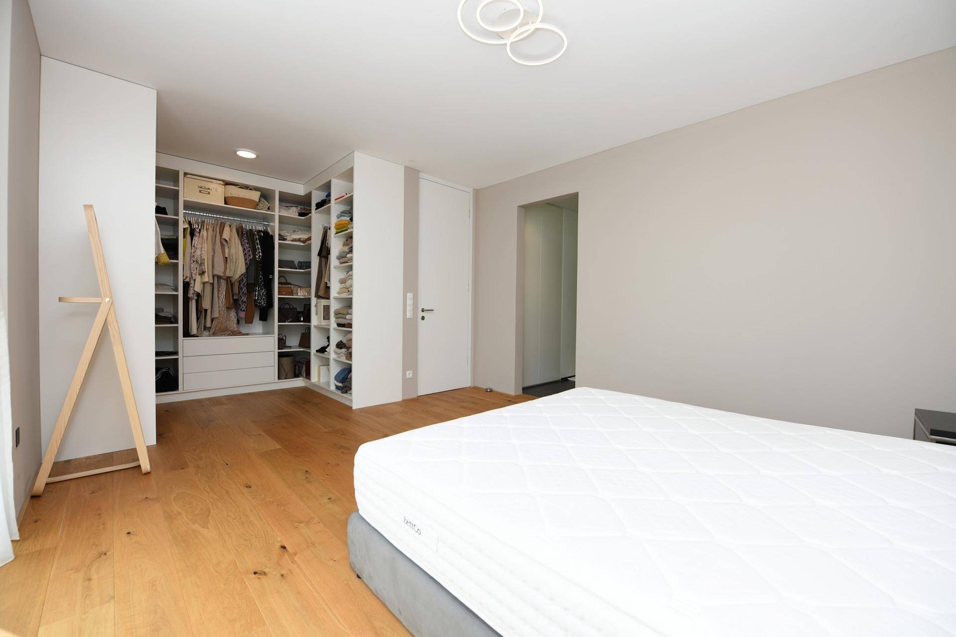 Helles Schlafzimmer mit Holzboden und integriertem begehbarem Kleiderschrank, modern gestaltet.