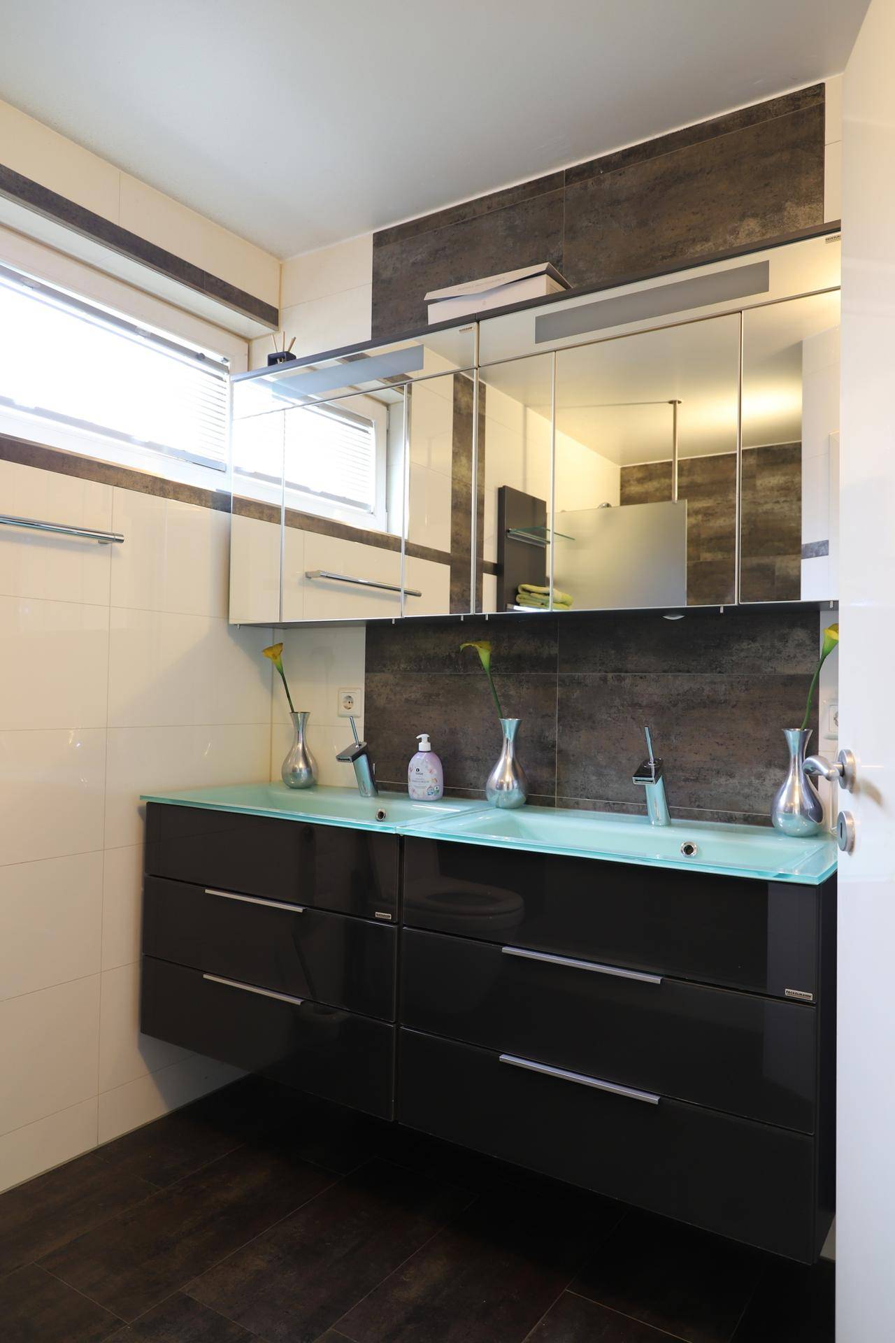 Modernes Badezimmer mit Doppelwaschbecken, großem Spiegelschrank und Fenster.