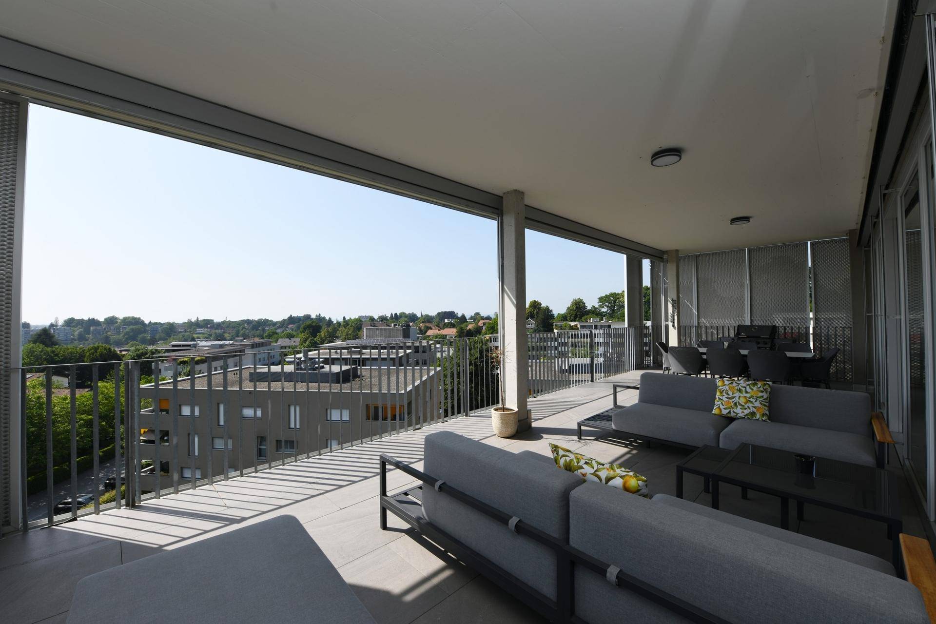 Weitläufige Terrasse mit bequemen Loungemöbeln und Panoramablick auf die Stadt.