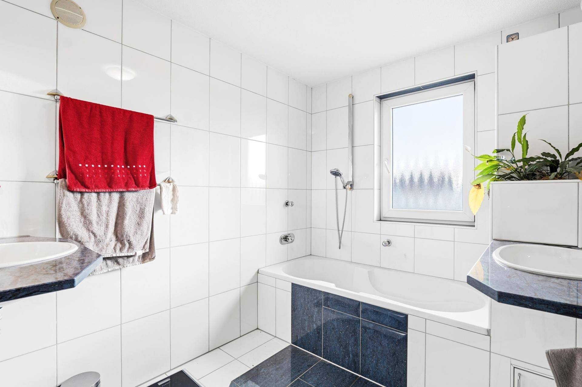 Modern gefliestes Badezimmer mit Badewanne, Dusche und zwei Waschbecken.