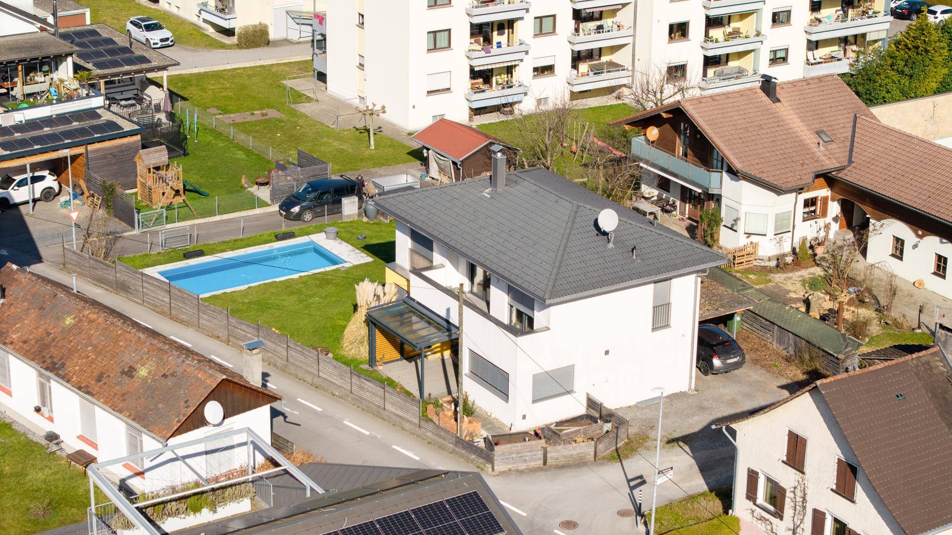 Luftaufnahme eines Wohngebiets mit Einfamilienhäusern und einem Pool im Garten.