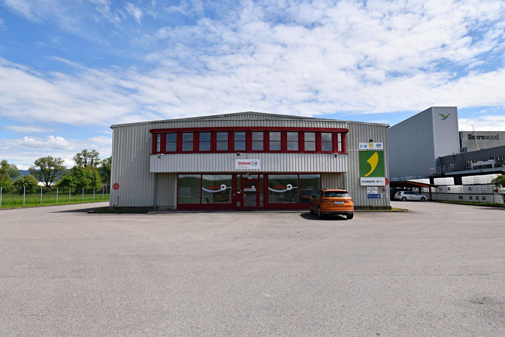 Frontansicht eines Geschäftsgebäudes mit großen Fenstern und einem geräumigen Parkplatz.