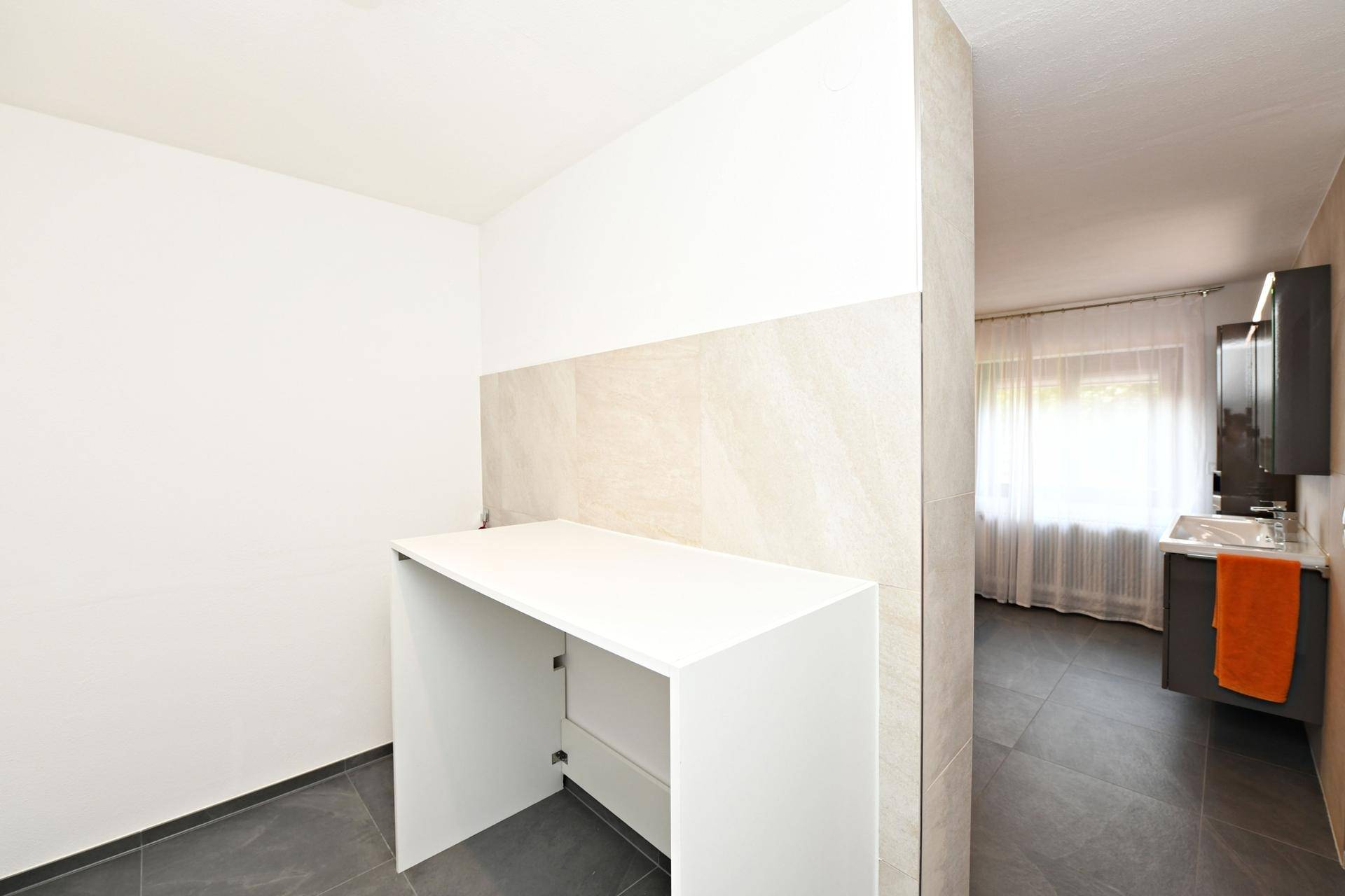 Heller Bereich mit Ablagefläche, angrenzend an ein modernes Badezimmer.