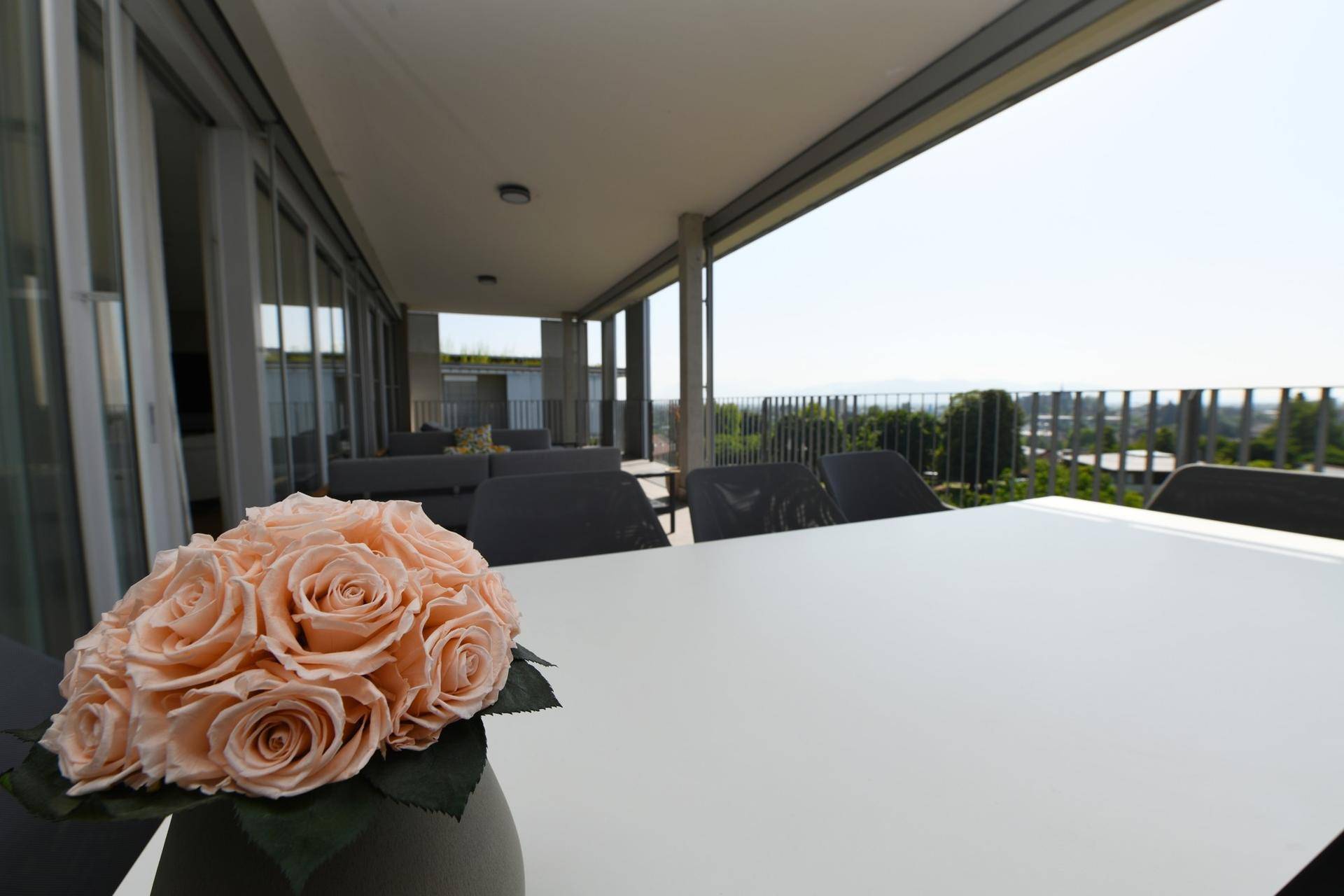 Dekoration auf dem Terrassentisch mit Blumen und weitem Blick über die Stadt.