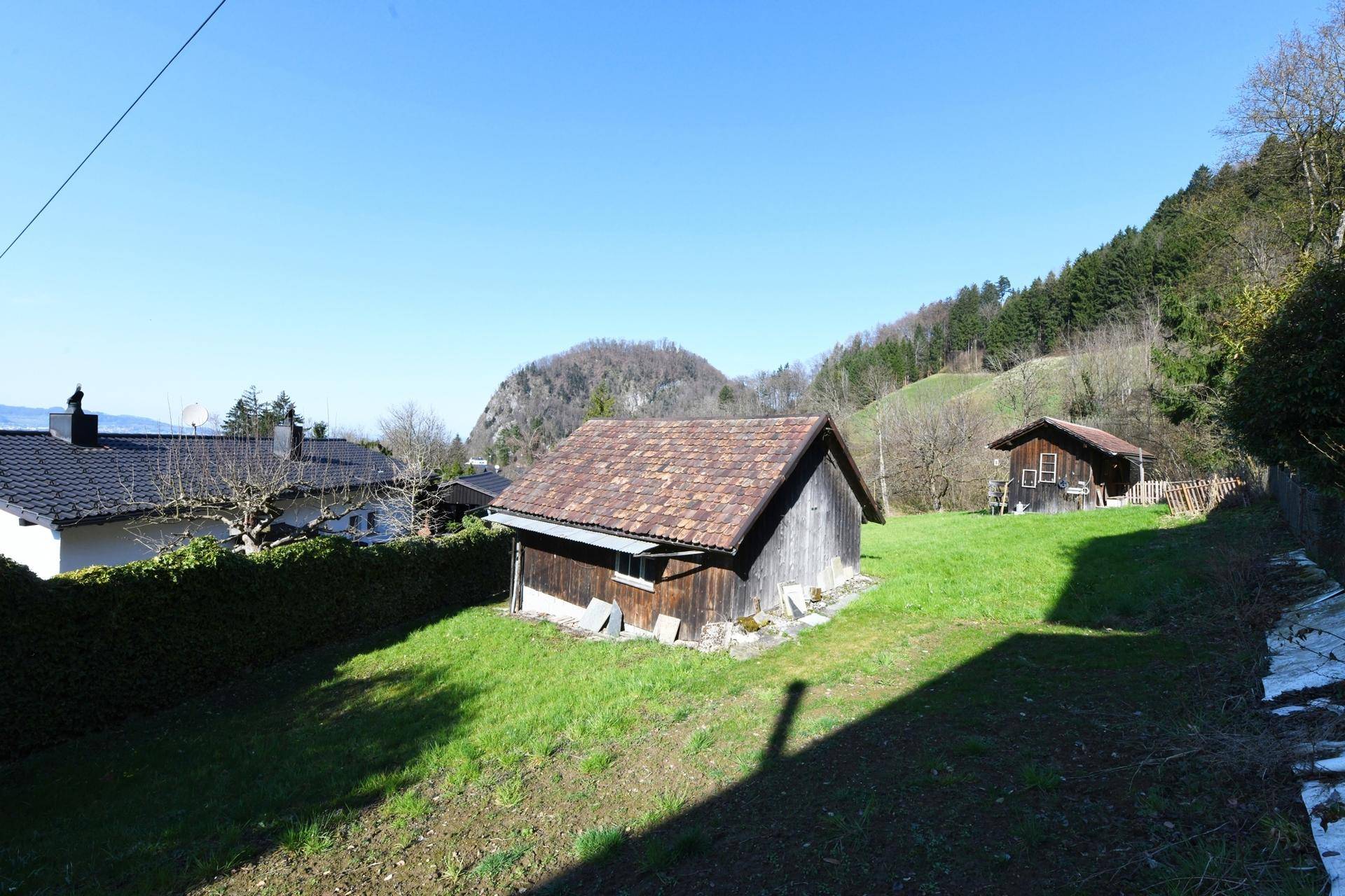 Gepflegter Gartenbereich mit Rasen, einem kleinen Holzschuppen und weitem Blick auf die Landschaft.