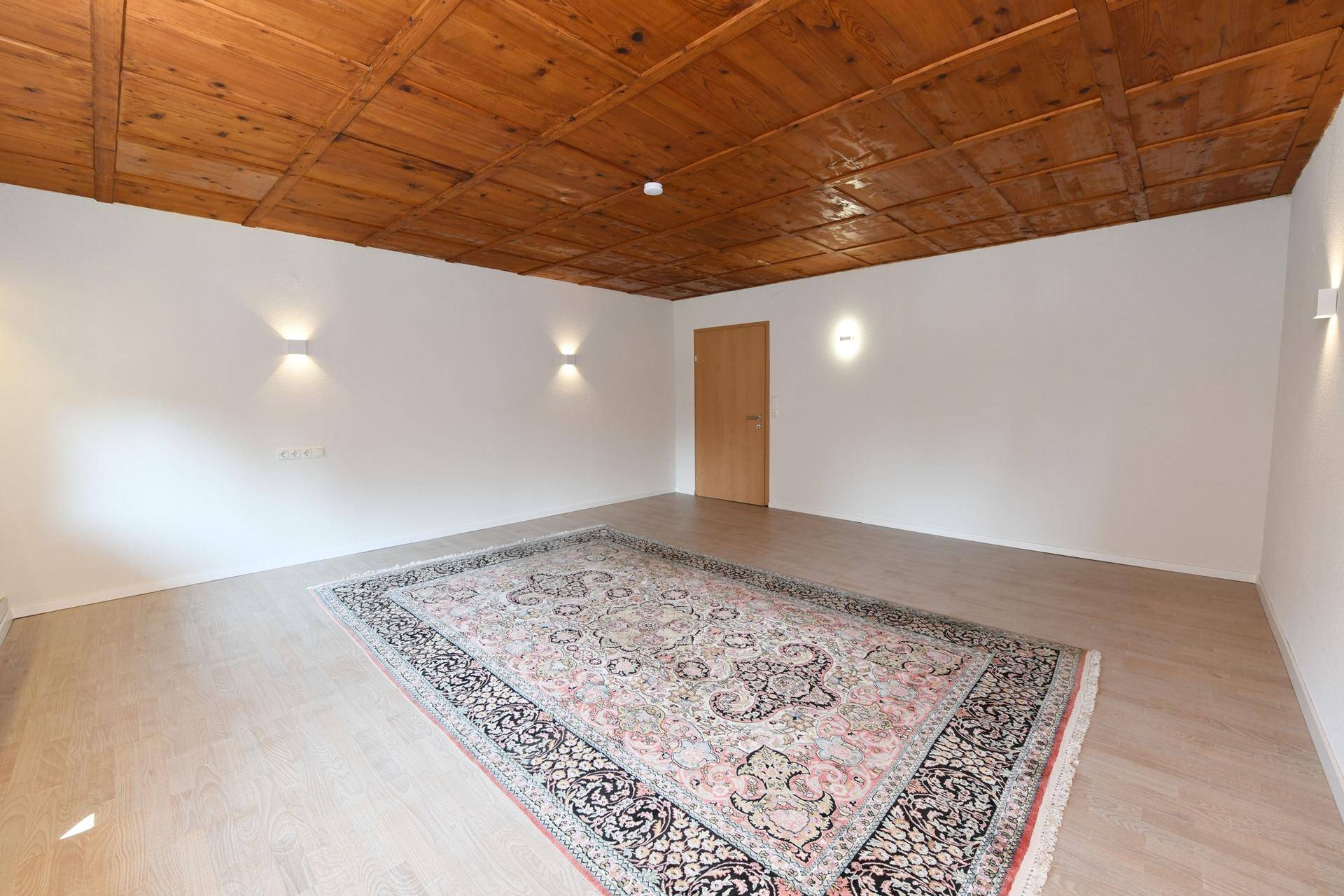 Helles Zimmer mit charakteristischer Holzkassettendecke und Parkettboden.