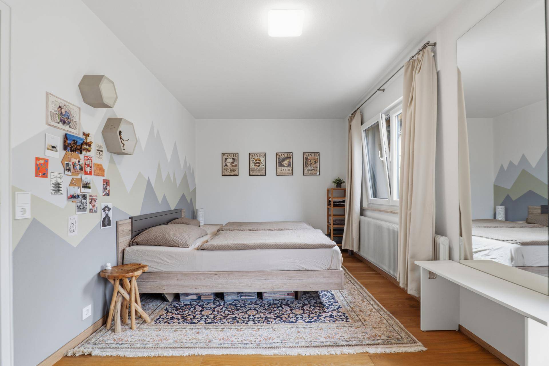 Gemütliches Schlafzimmer mit Holzbett, Parkettboden und dekorativer Wandgestaltung.