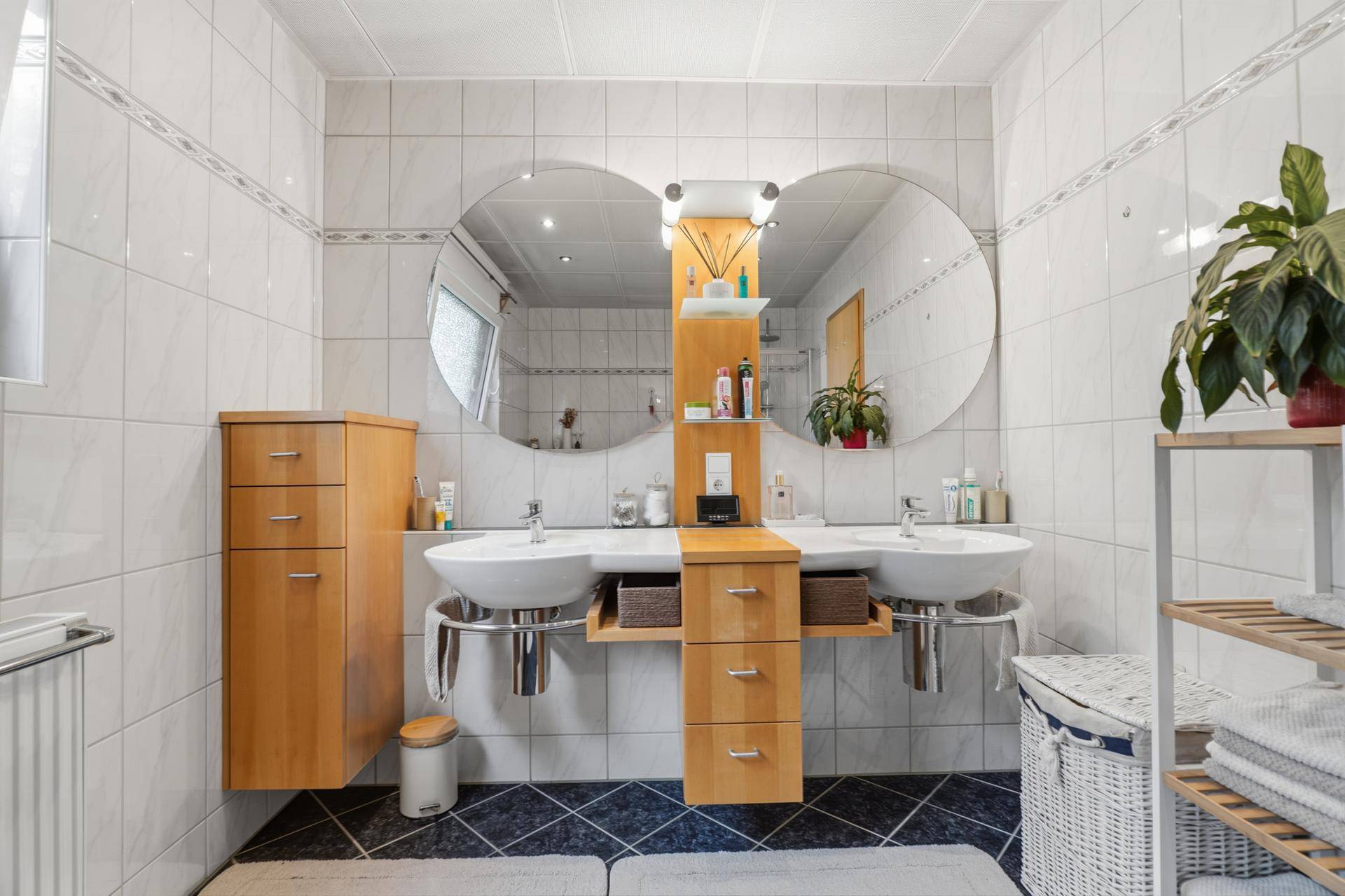 Geräumiges Badezimmer mit Doppelwaschbecken, großen Spiegeln und Fliesenboden.