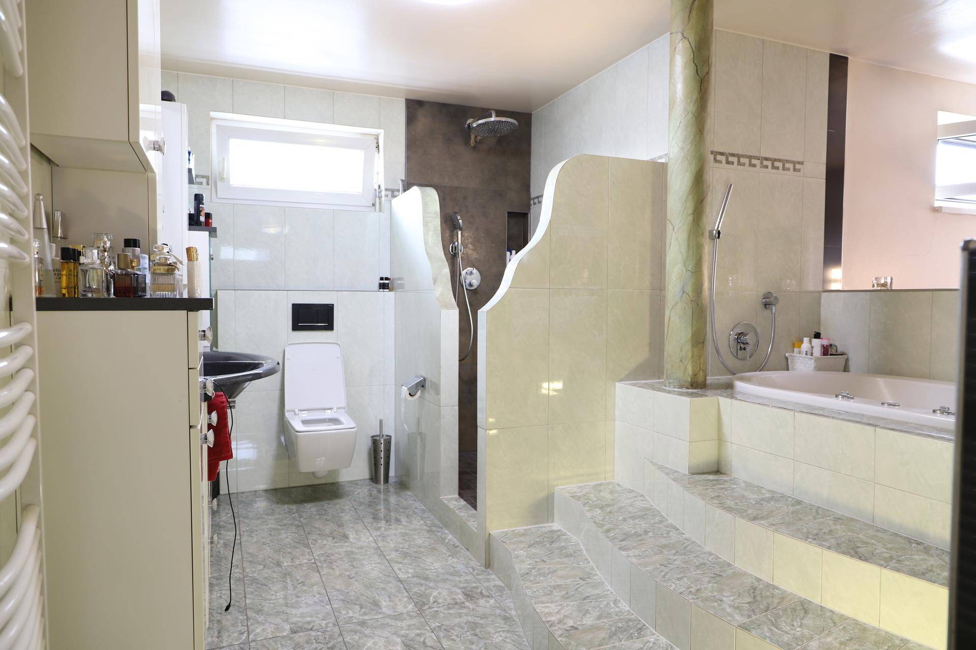 Geräumiges Badezimmer mit Dusche, Badewanne, WC und Fenster für natürliches Licht.