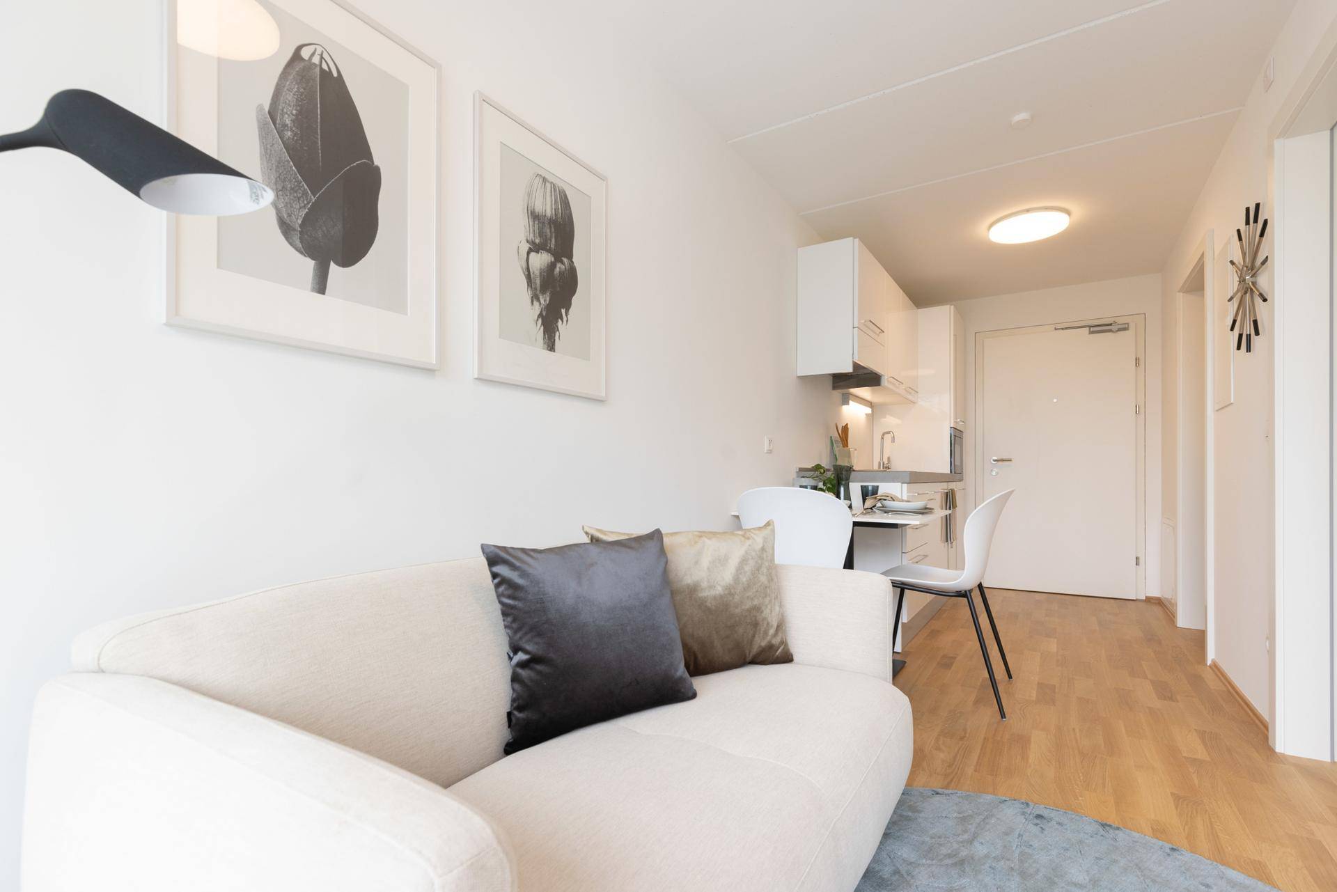Gemütlicher Wohnbereich mit hellem Sofa, Esstisch und integrierter Küchenzeile in offener Gestaltung.