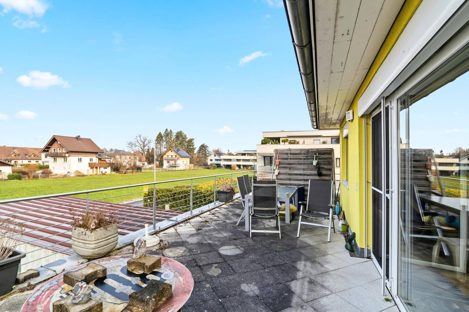 Große gepflasterte Terrasse mit Gartenmöbeln und weitem Blick ins Grüne.