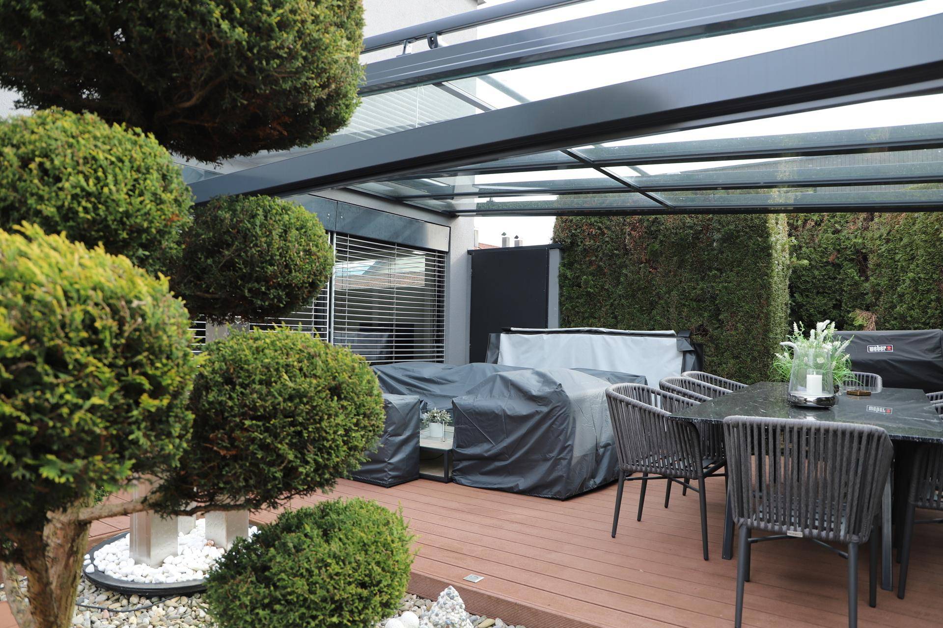 Detailansicht des überdachten Terrassenbereichs mit stilvollen Gartenmöbeln und Dekoration.