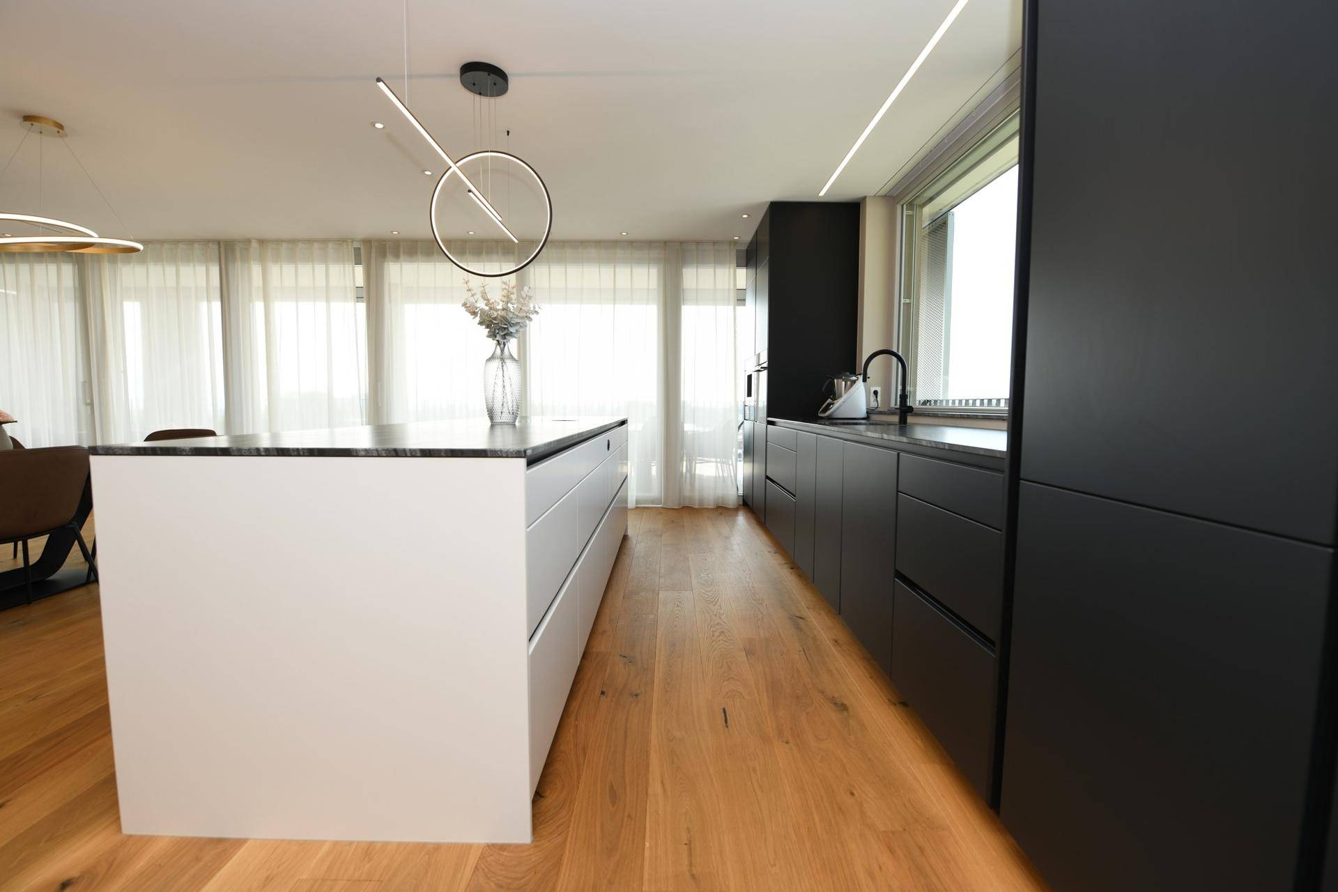 Elegante Küche mit schwarzer Arbeitsplatte, Kücheninsel und Holzboden.