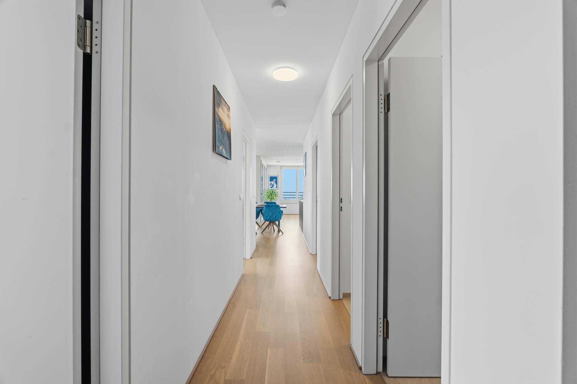 Langer, heller Flur mit Holzboden, der zu den Wohnbereichen der Wohnung führt.
