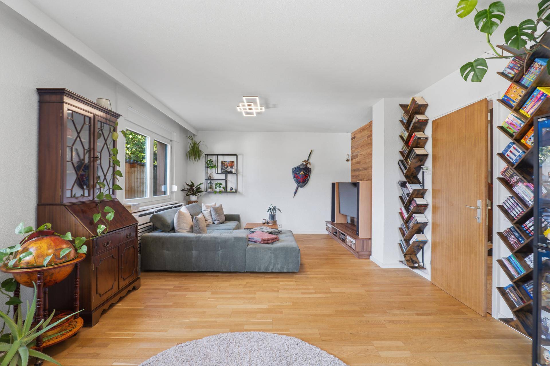 Geräumiges Wohnzimmer mit Holzboden, Bücherregalen und einem gemütlichen Sofa.