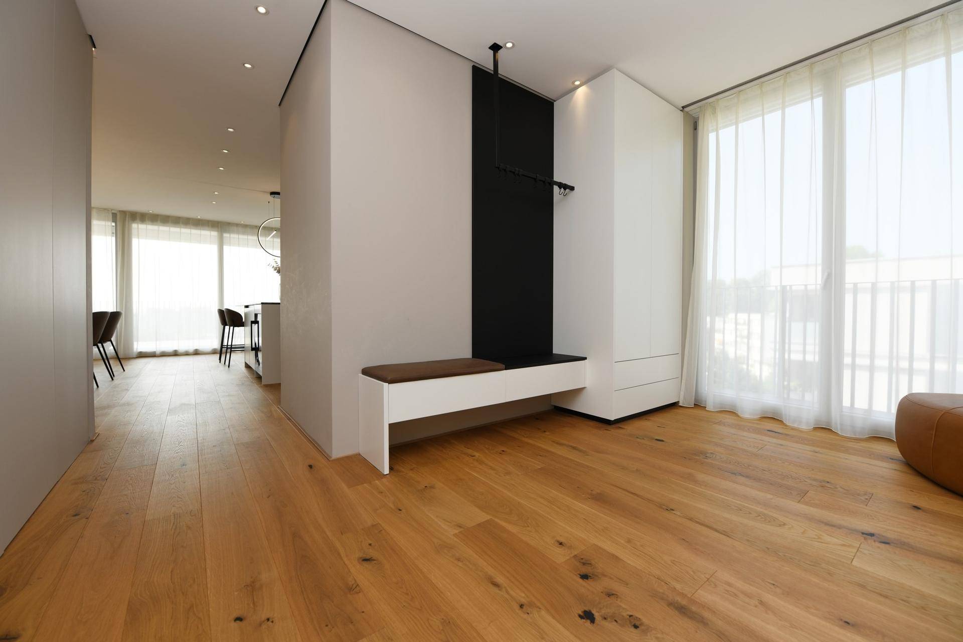 Heller Eingangsbereich mit Holzboden, Garderobe und Blick in den offenen Wohnbereich.