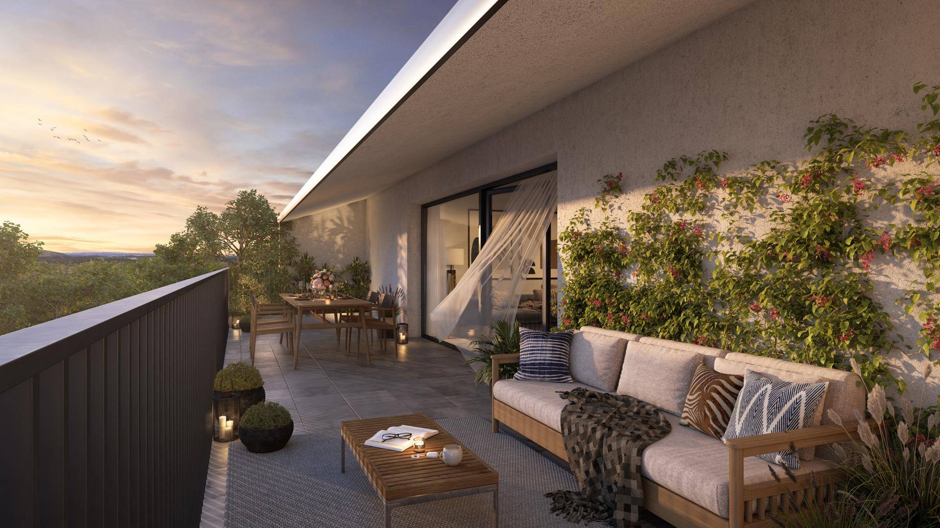 Geräumiger Balkon mit bequemen Loungemöbeln und Blick ins Grüne bei Sonnenuntergang.