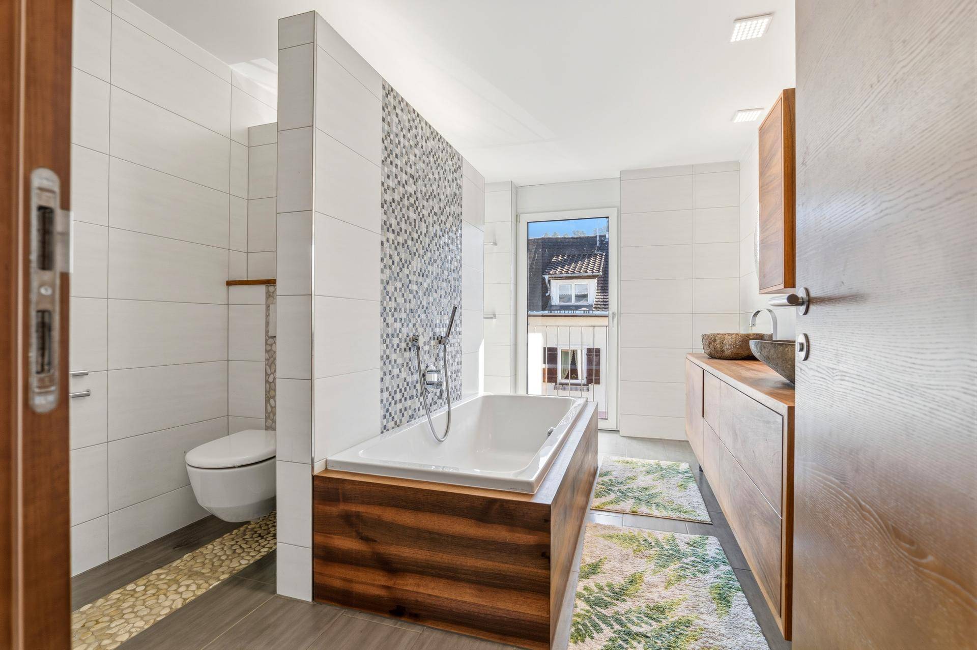 Modernes Badezimmer mit Badewanne, Doppelwaschbecken und Holzelementen.