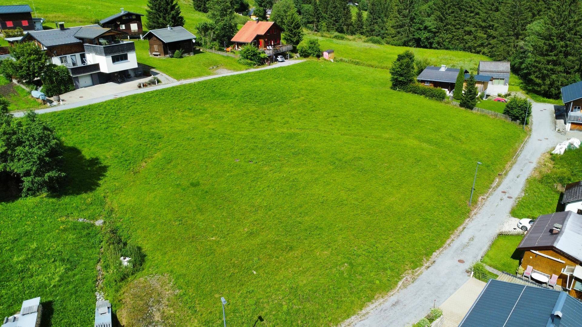 Weitläufiges grünes Grundstück aus der Vogelperspektive mit angrenzenden Wohnhäusern und Wegen.