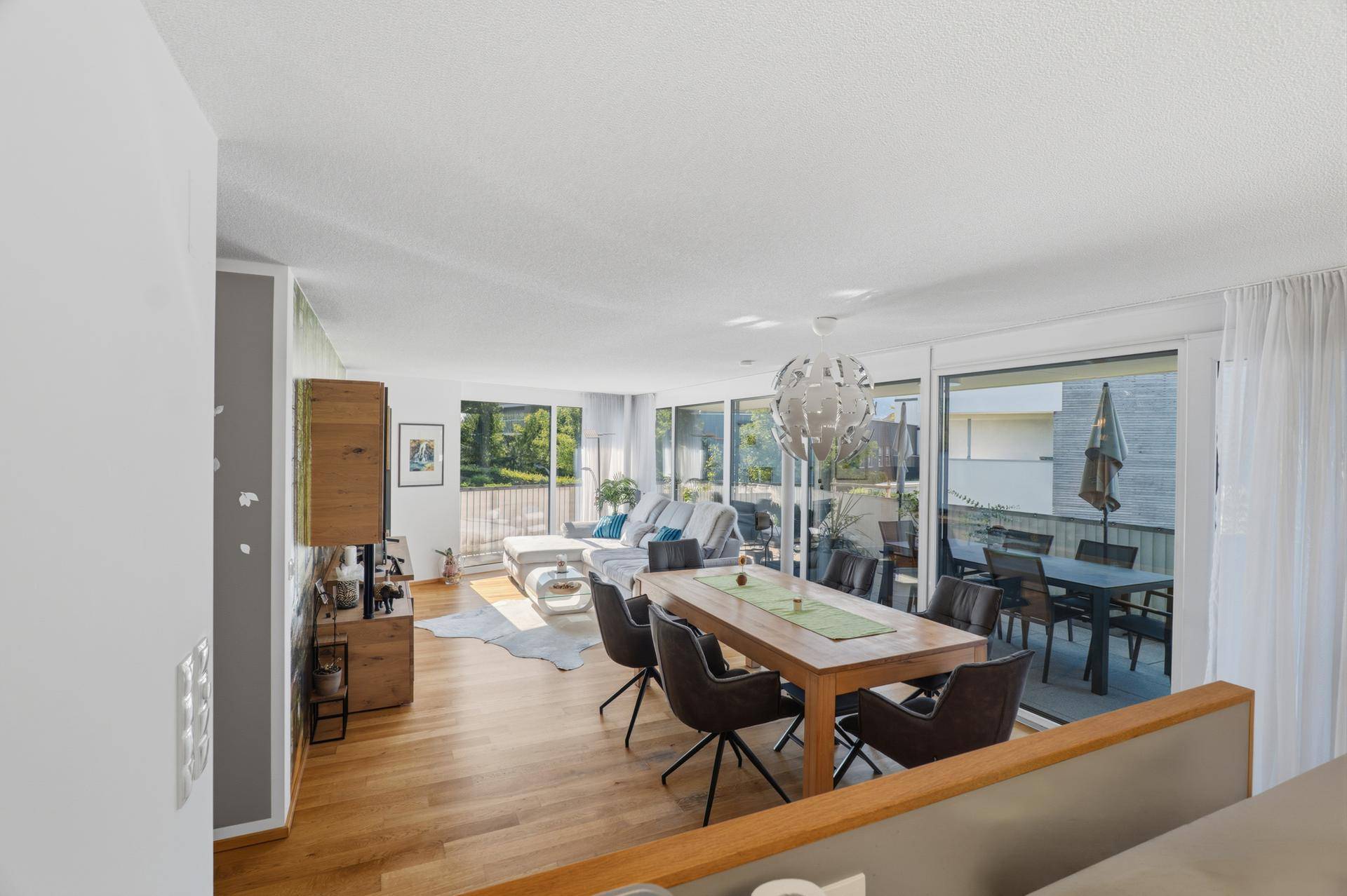 Geräumiger Wohn- und Essbereich mit Holzboden, modernem Esstisch und Zugang zur Terrasse.
