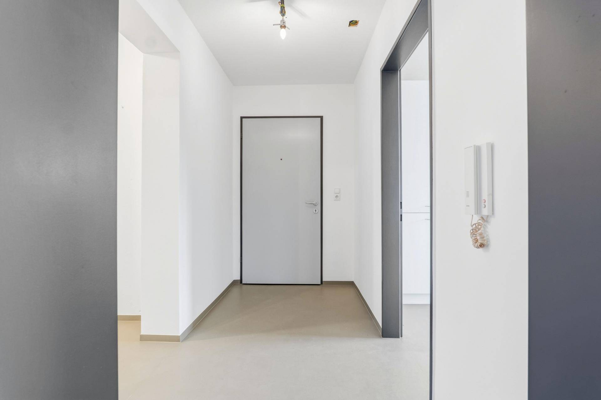 Heller Eingangsbereich mit moderner Tür und Gegensprechanlage.