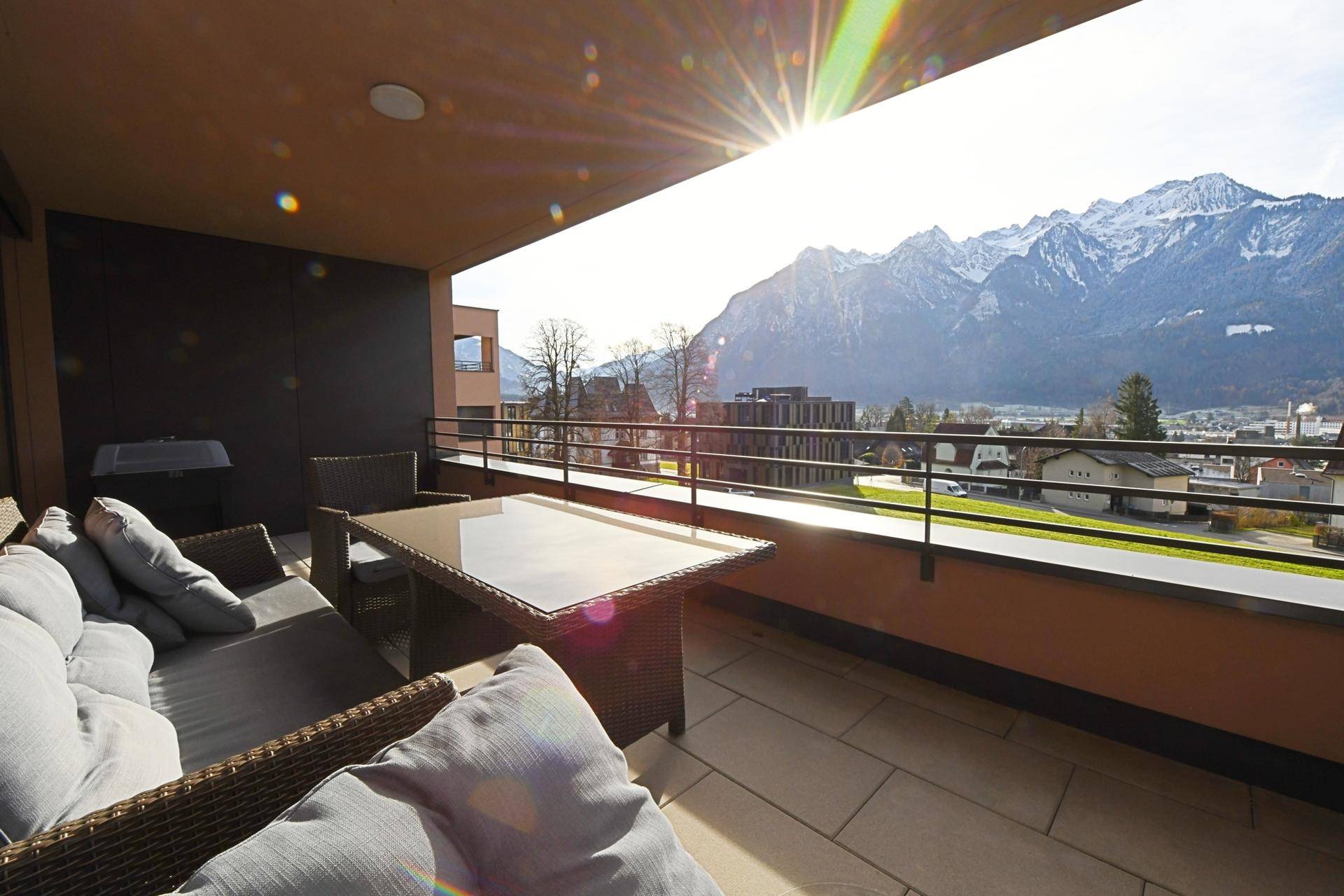 Sonniger Balkon mit bequemen Möbeln und weitem Blick auf die Berge.