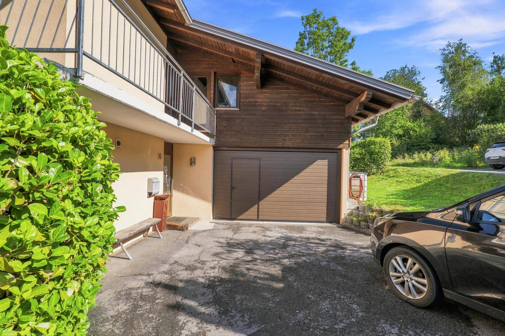 Außenansicht des Hauses mit Garage und Zufahrt, umgeben von Grünflächen.