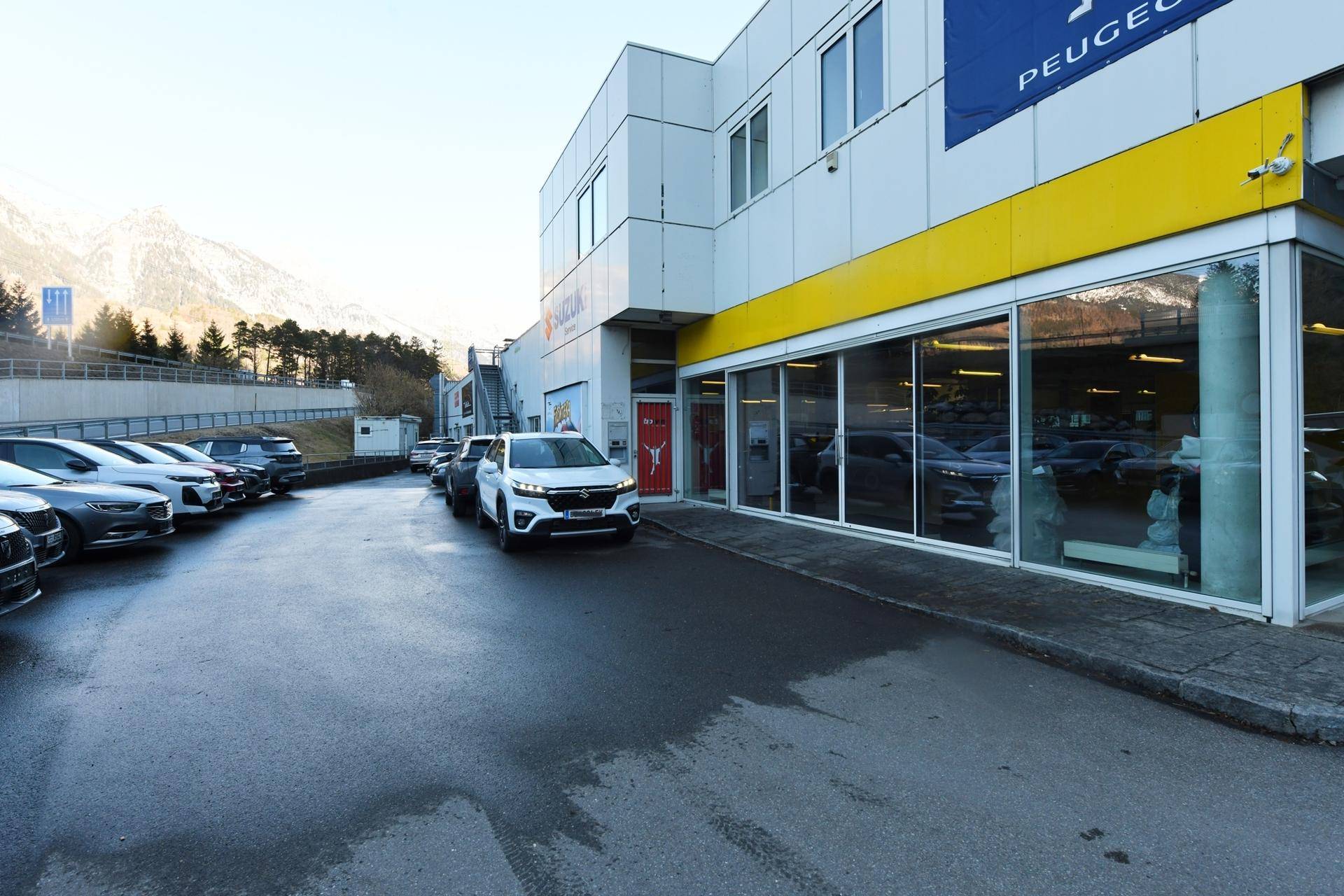 Seitenansicht eines Autohauses mit Parkplätzen und großen Schaufenstern, modern und einladend.