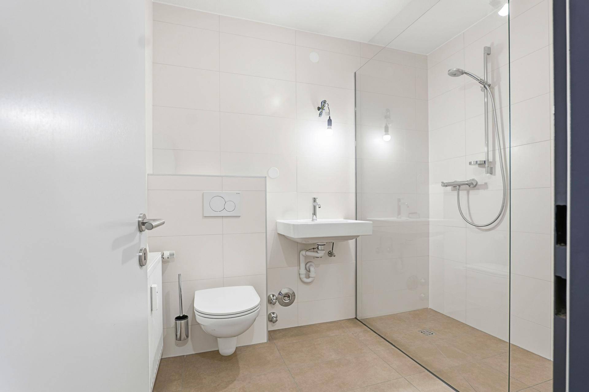 Modernes Badezimmer mit weiß gefliesten Wänden, ebenerdiger Dusche und Hänge-WC.