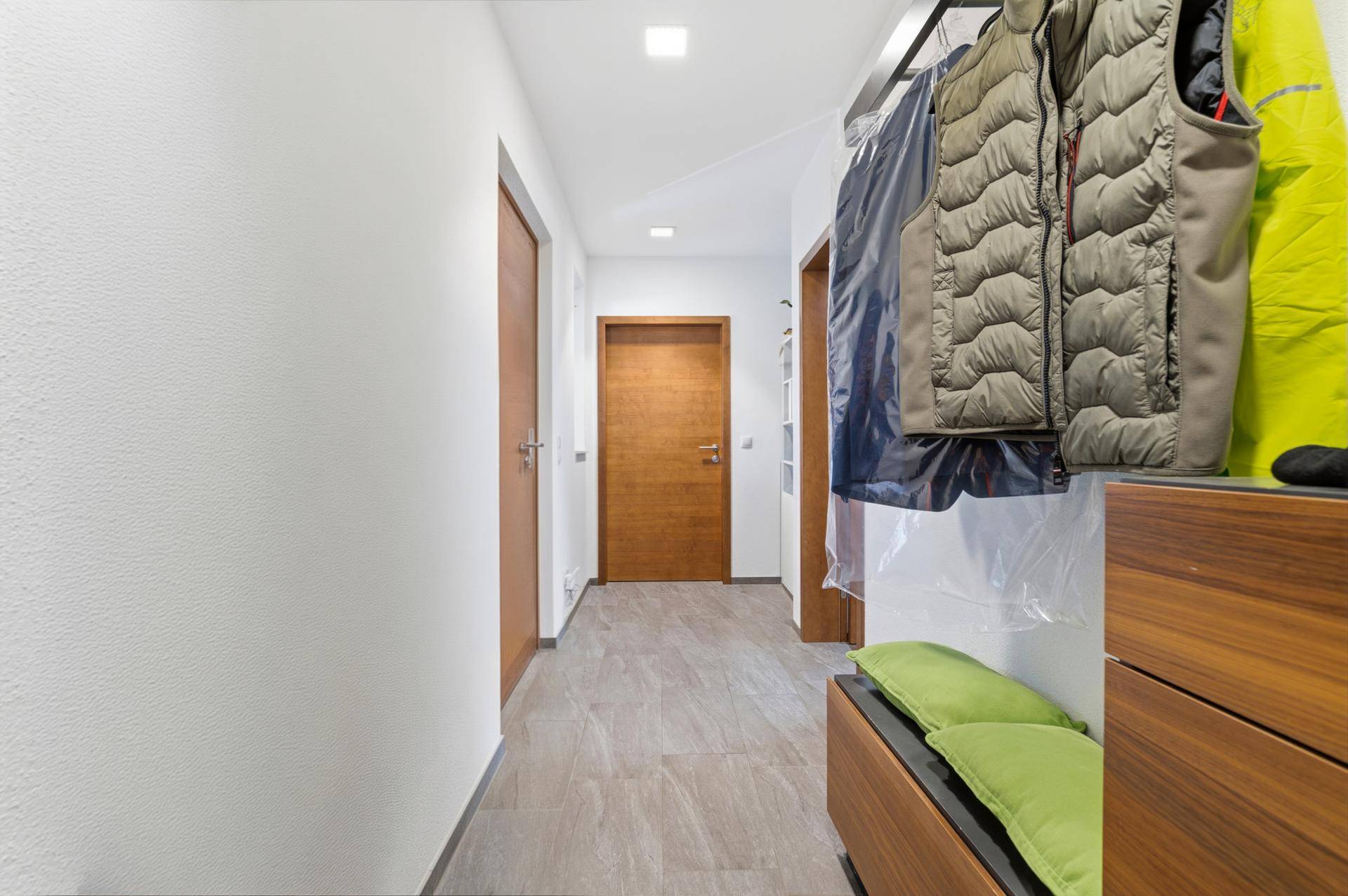 Heller Flur mit Fliesenboden und Garderobe, der zu den Schlafzimmern führt.