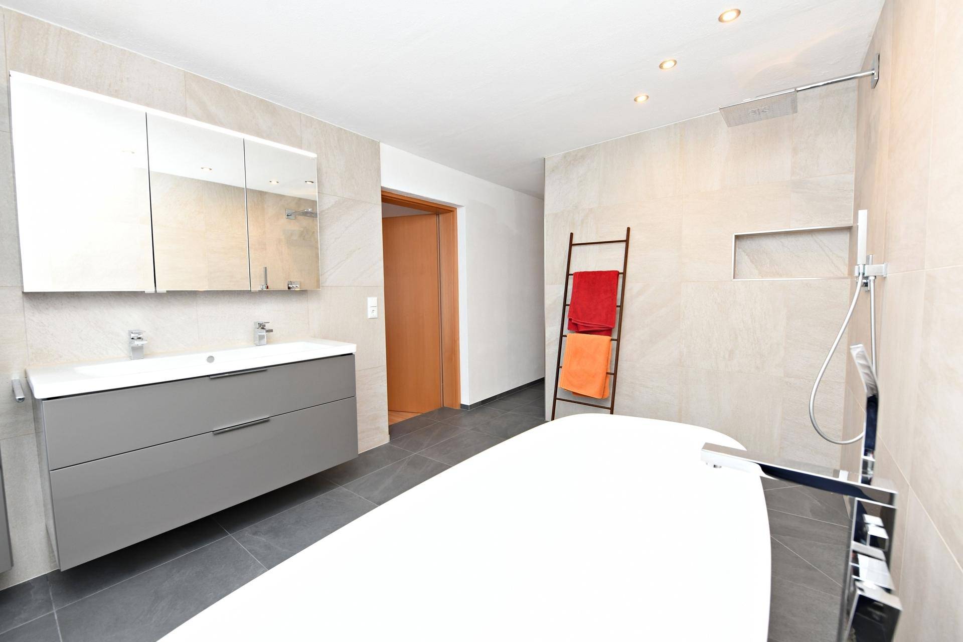 Elegantes Badezimmer mit Doppelwaschbecken, Spiegelschrank und freistehender Badewanne.