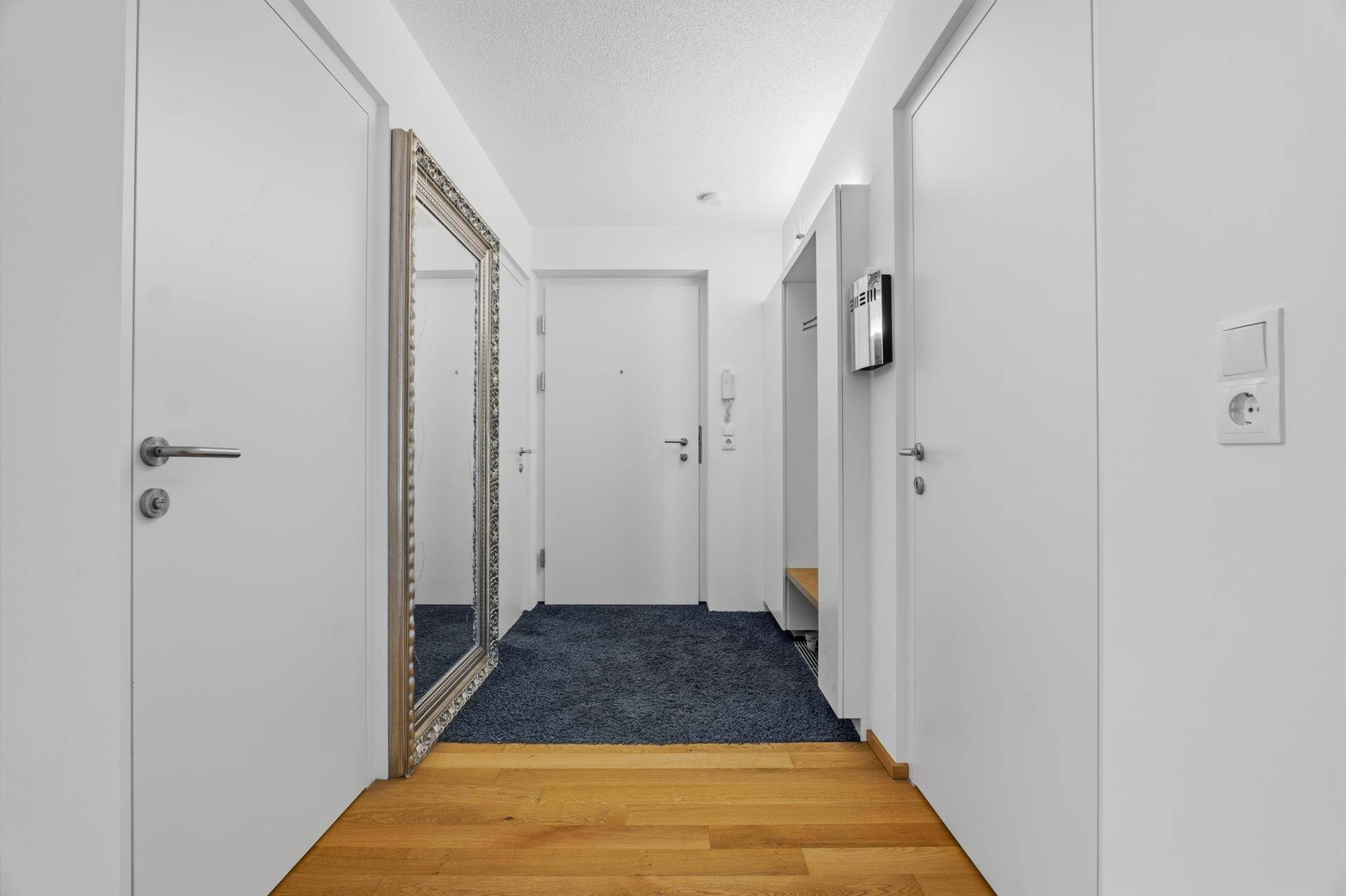 Heller Eingangsbereich mit Holzboden, Garderobe und großem Spiegel.