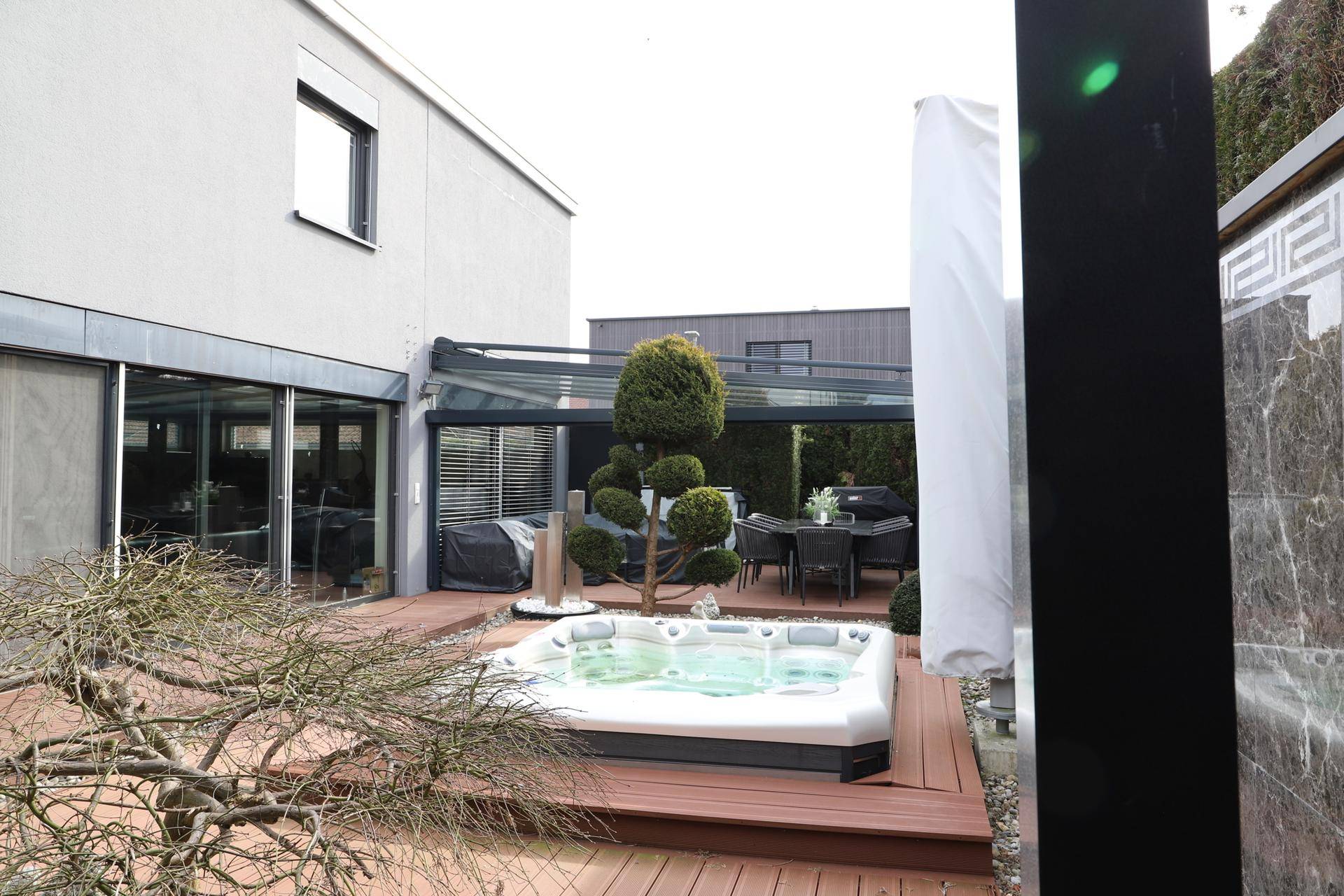 Exklusiver Außenbereich mit Whirlpool auf Holzdeck und überdachtem Essbereich im Garten.