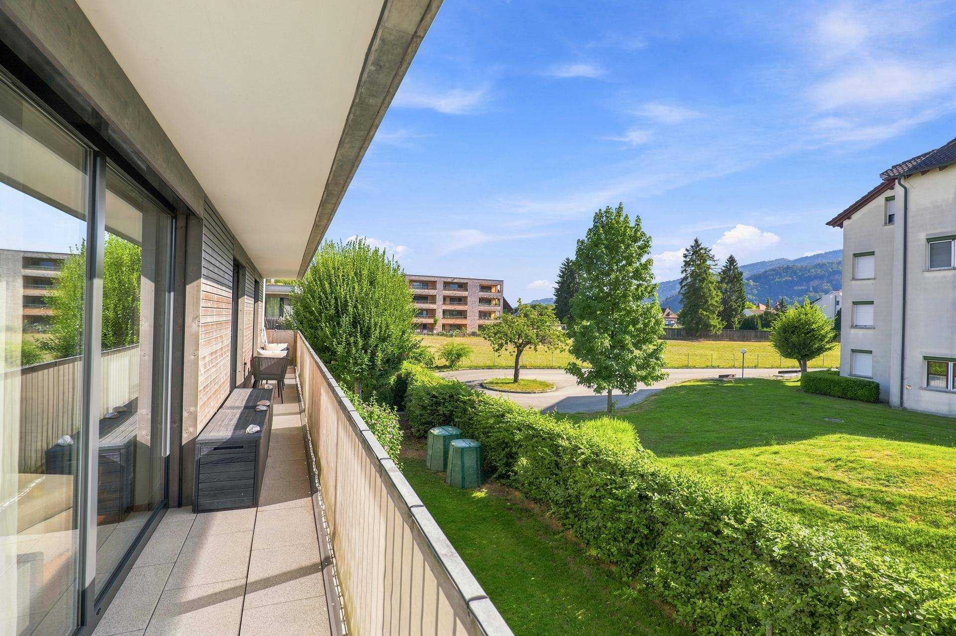 Langer Balkon mit Blick auf die gepflegte Rasenfläche und grüne Umgebung.