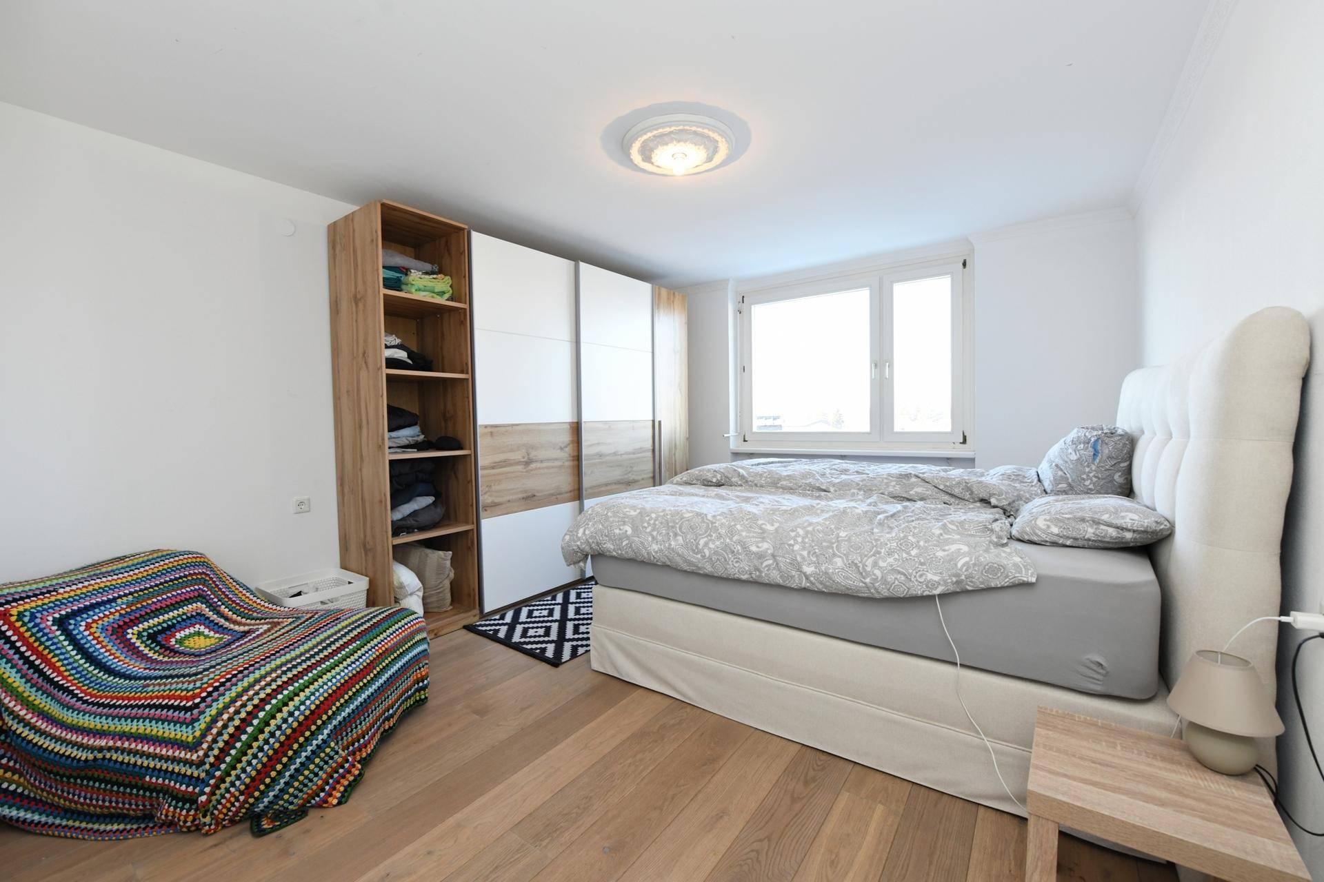Helles Schlafzimmer mit Doppelbett, Kleiderschrank und Holzboden.