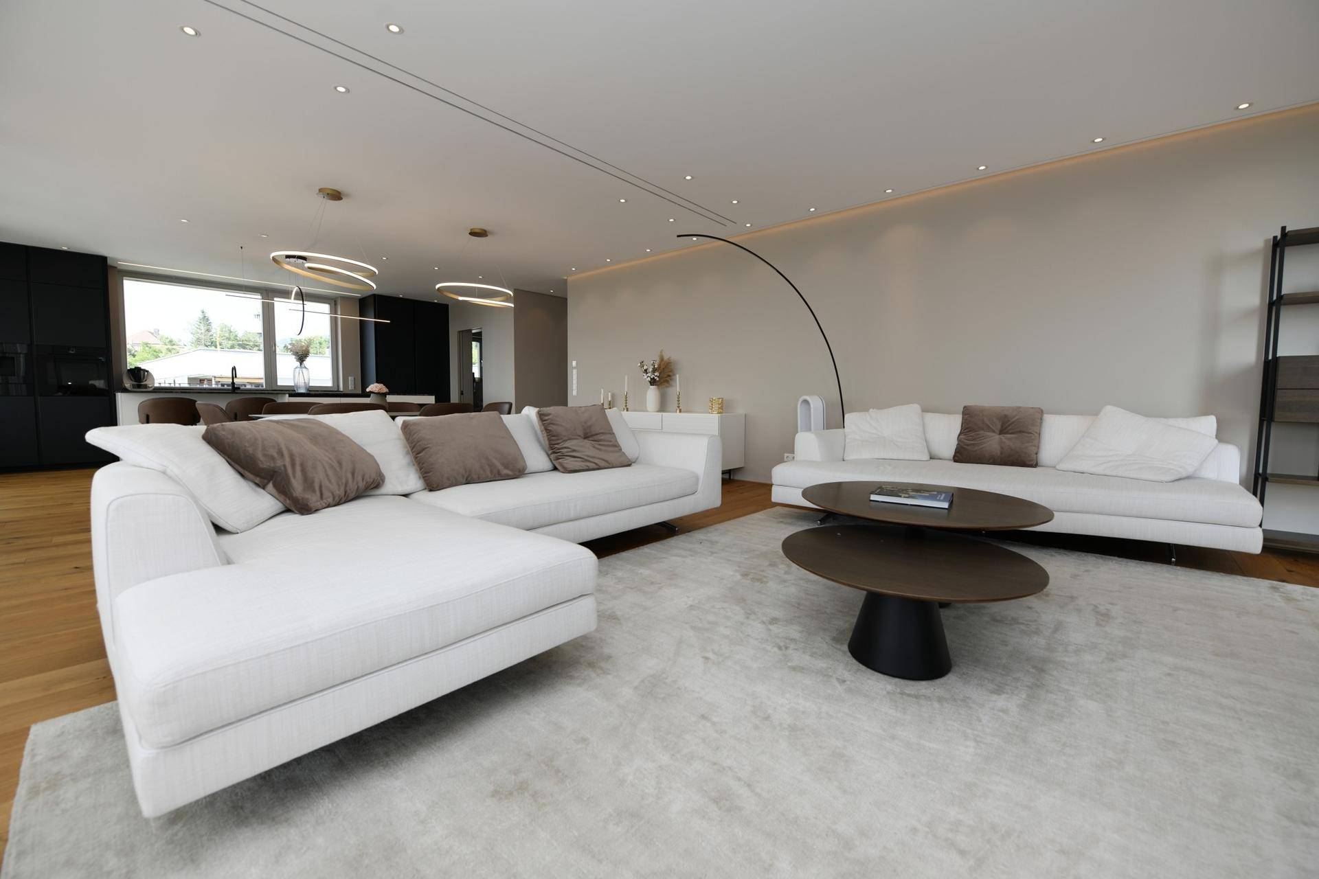 Geräumiges Wohnzimmer mit bequemen weißen Sofas, Holzboden und moderner Einrichtung.