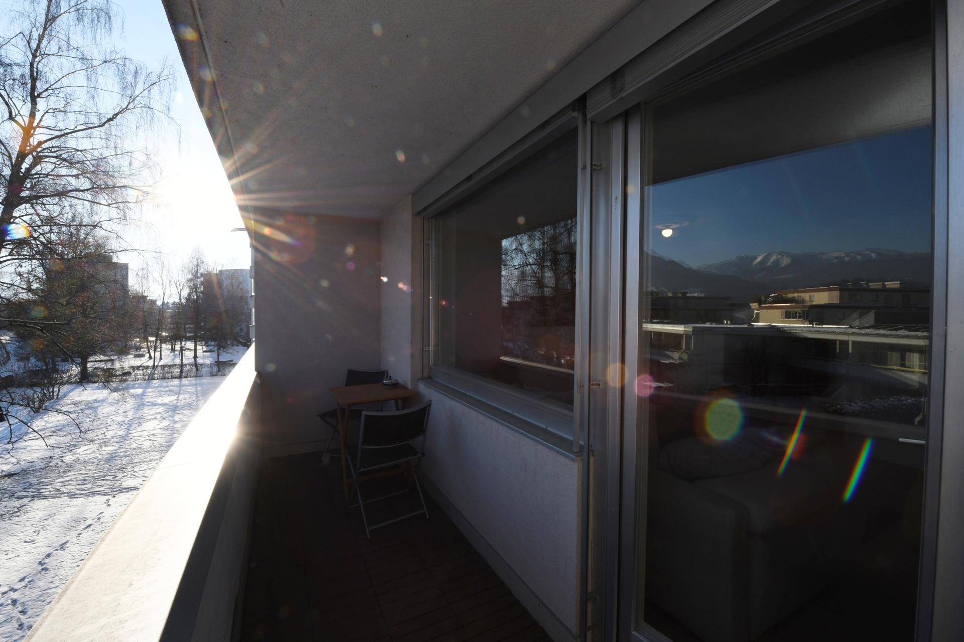 Heller Balkon mit Sonnenschein und Blick auf die verschneite Umgebung.