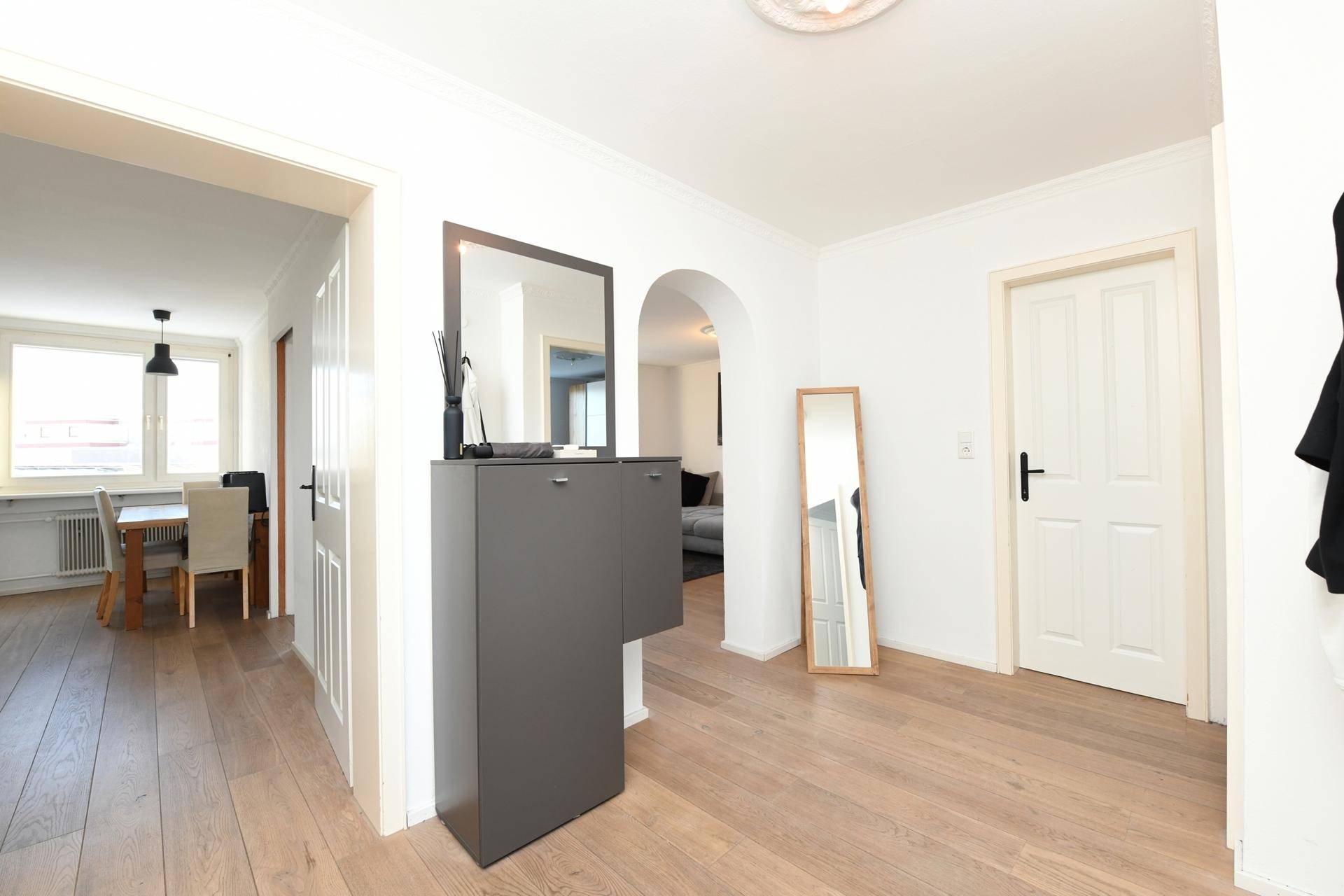 Geräumiger Flur mit Holzboden und Spiegel, verbindet die Wohnbereiche.