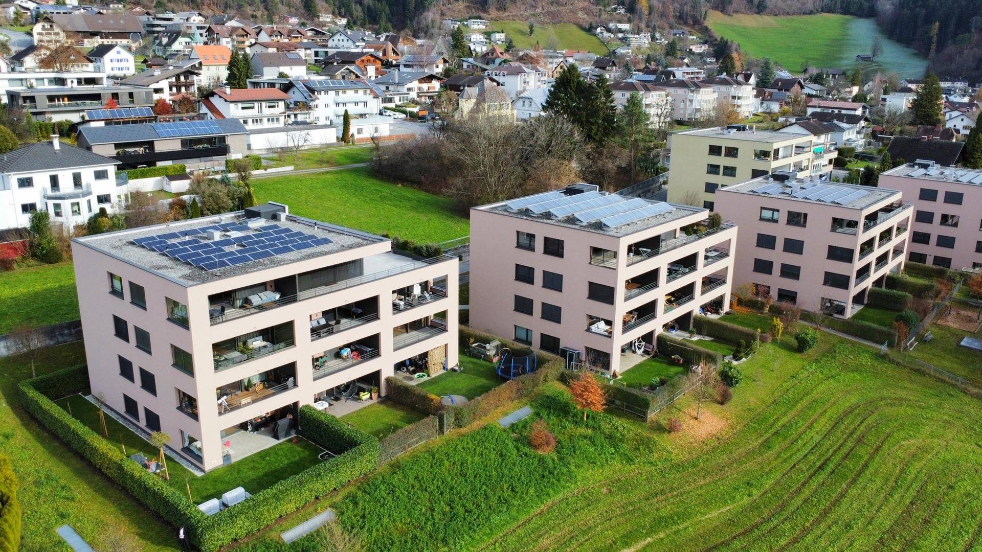 Luftaufnahme einer Wohnsiedlung mit mehreren modernen Gebäuden und Solaranlagen.