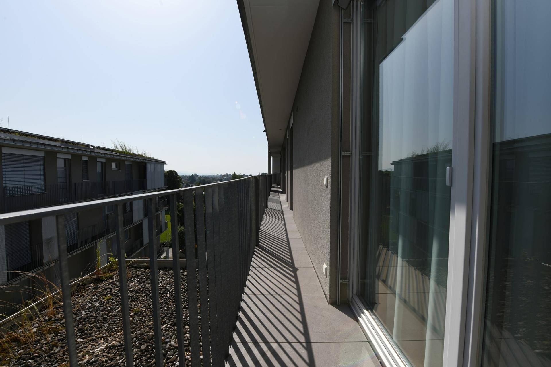 Langer, schmaler Balkon entlang der Gebäudeseite mit Metallgeländer.