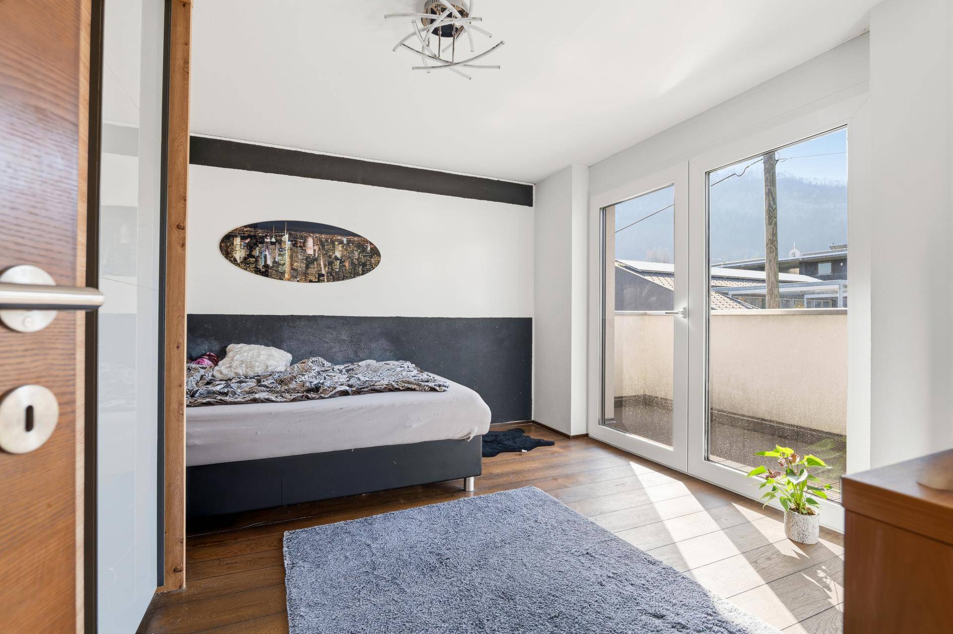 Schlafzimmer mit Holzboden, Doppelbett und Zugang zu einem Außenbereich.