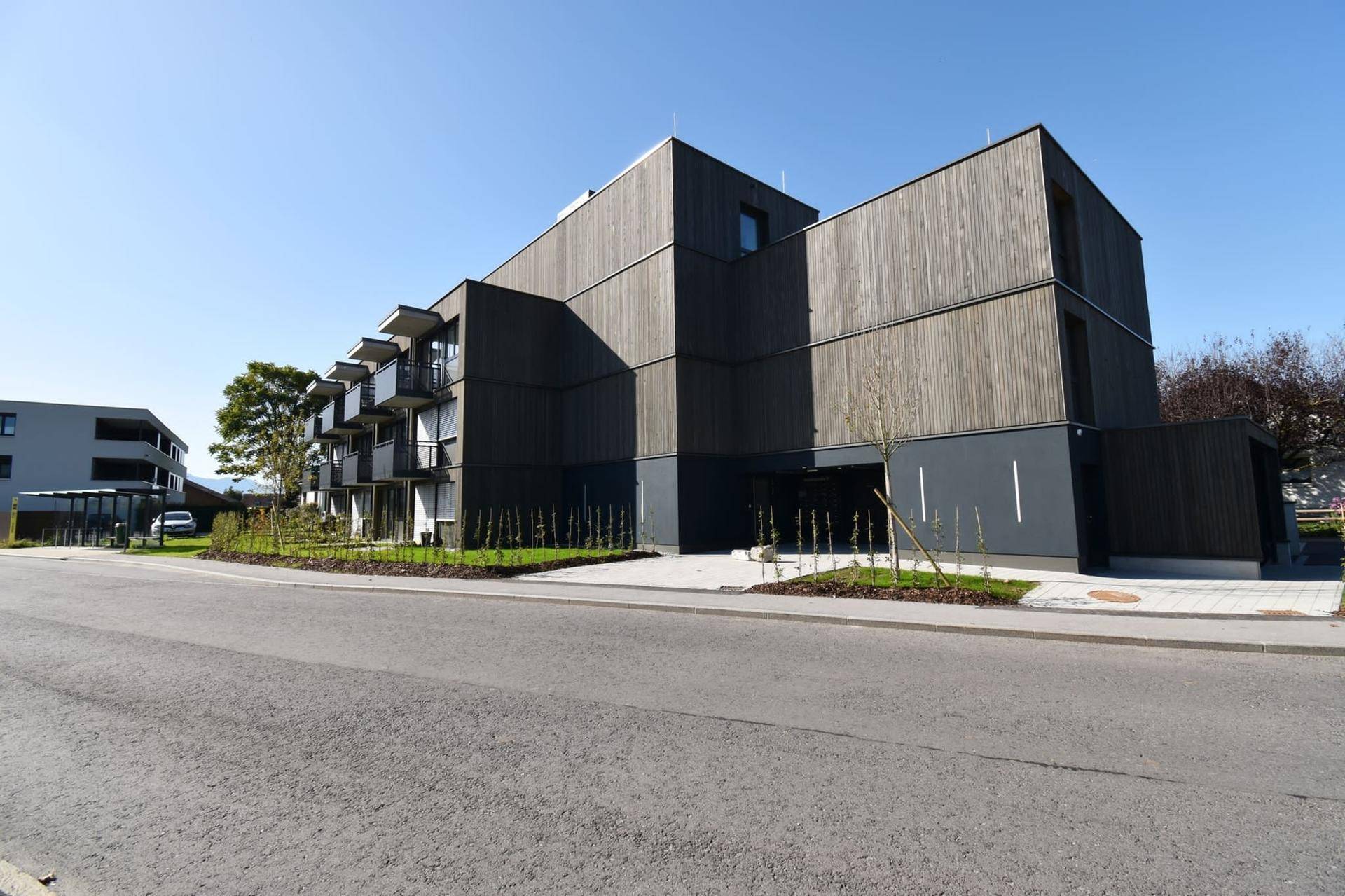 Zeitgenössisches Wohngebäude mit markanter Holzverkleidung und moderner Architektur unter blauem Himmel.