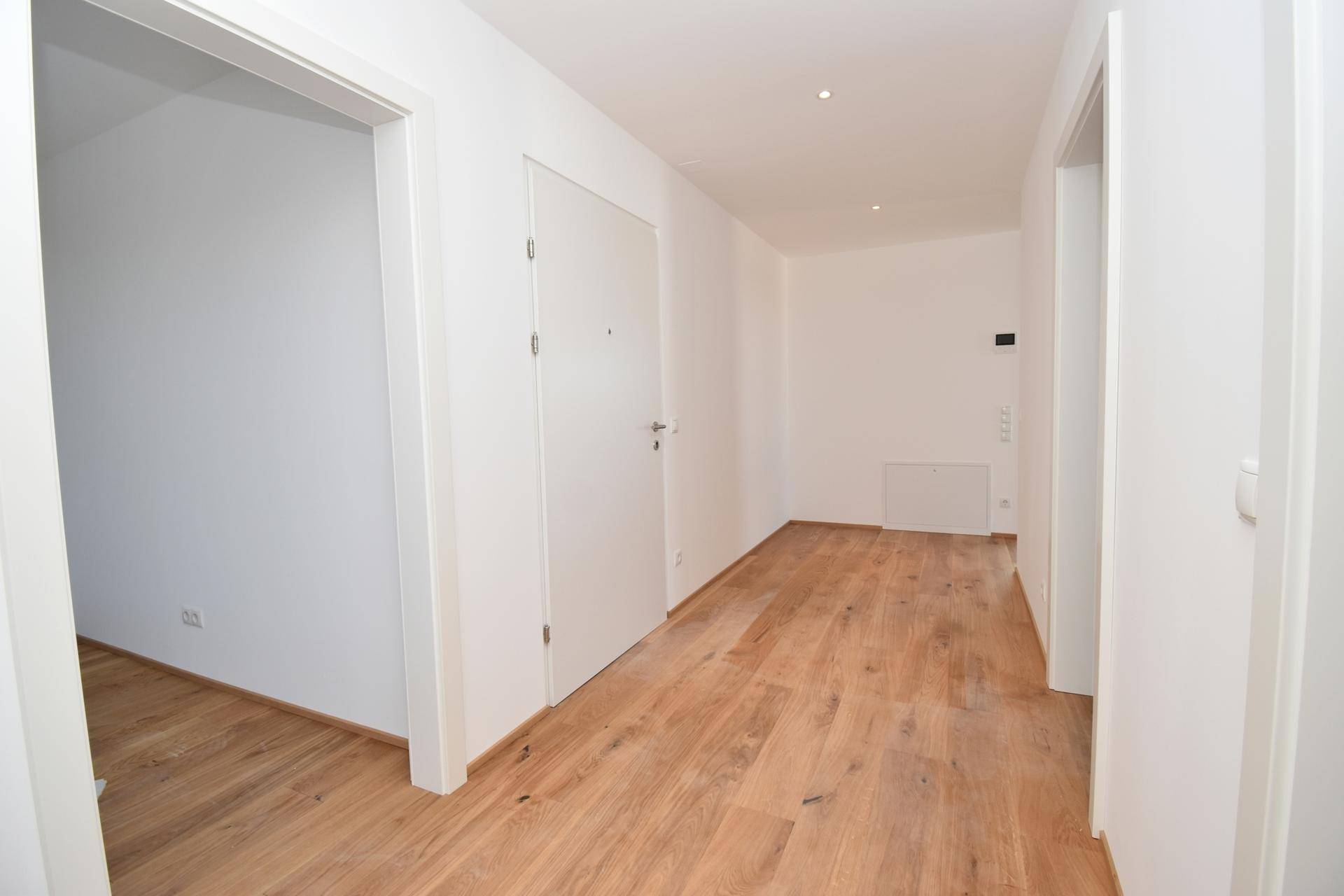 Heller Flur mit Holzparkettboden und weißen Türen, der zu den weiteren Räumen führt.