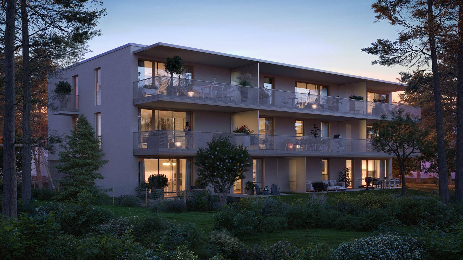 Moderne Wohnanlage mit großzügigen Balkonen und Terrassen, umgeben von viel Grün bei Abenddämmerung.