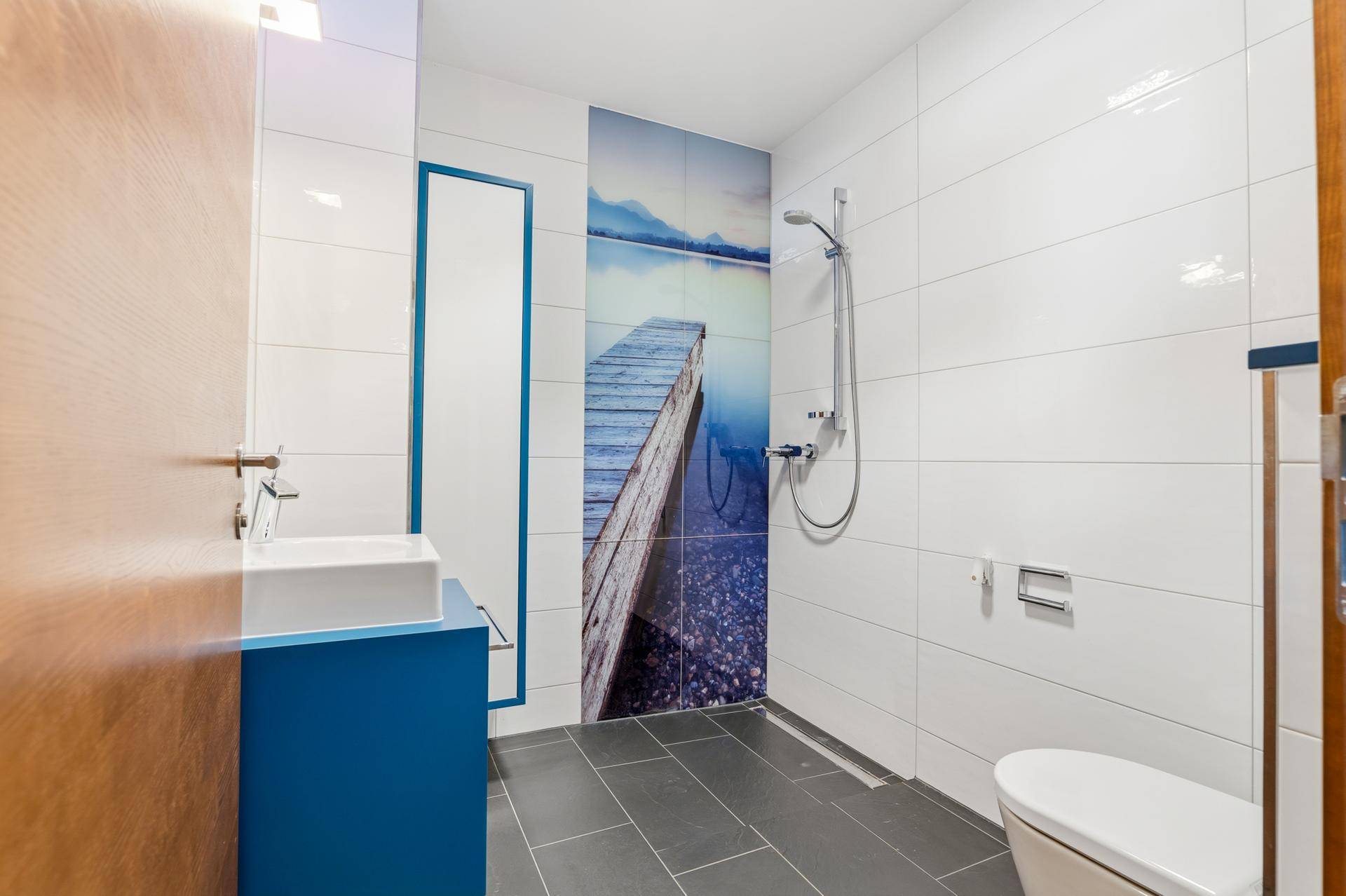 Modernes Badezimmer mit Dusche, Waschbecken und dekorativer Wandfliese.