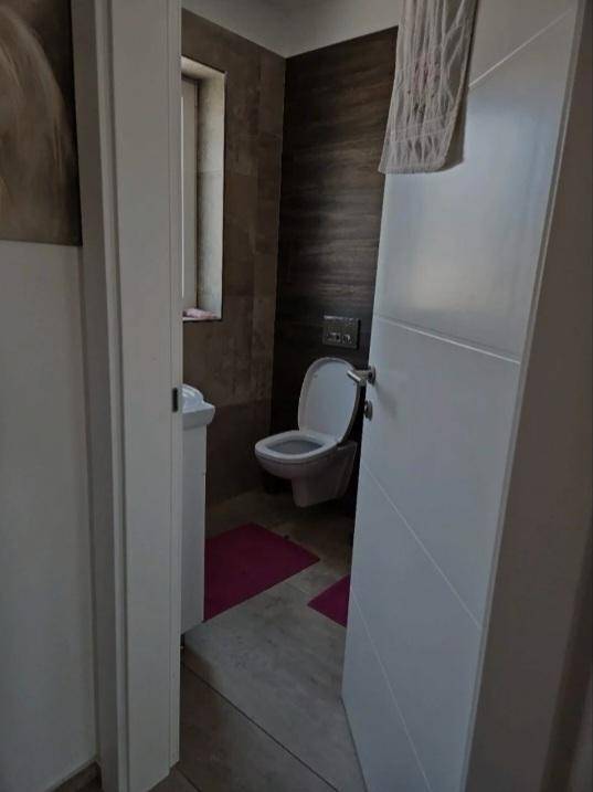 Modernes Gäste-WC mit Wand-WC, kleinem Waschbecken und dunklen Wandfliesen.