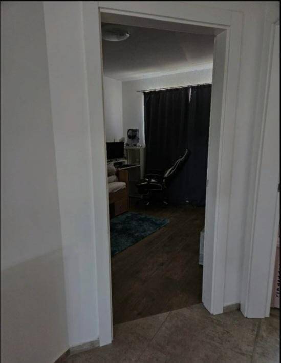 Blick in einen Raum mit dunklen Vorhängen und Holzoptik-Boden.