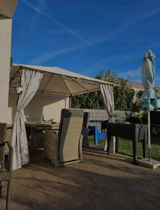 Gemütlicher Außenbereich mit überdachter Terrasse, Gartenmöbeln und Blick ins Grüne.