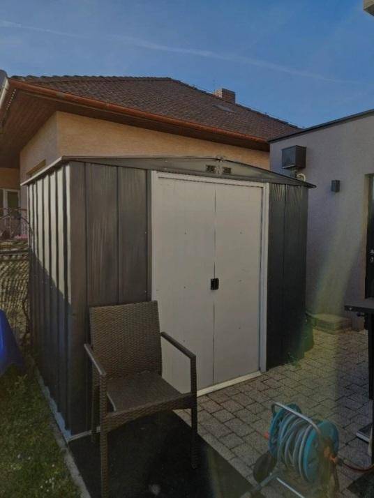 Praktischer Gartenschuppen auf gepflastertem Bereich neben dem Haus.