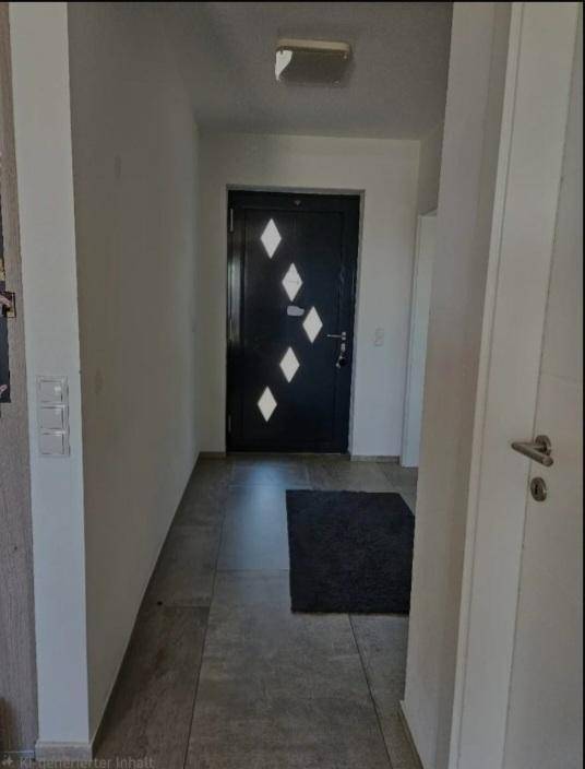 Heller Eingangsbereich mit dunkler Haustür und Fliesenboden.